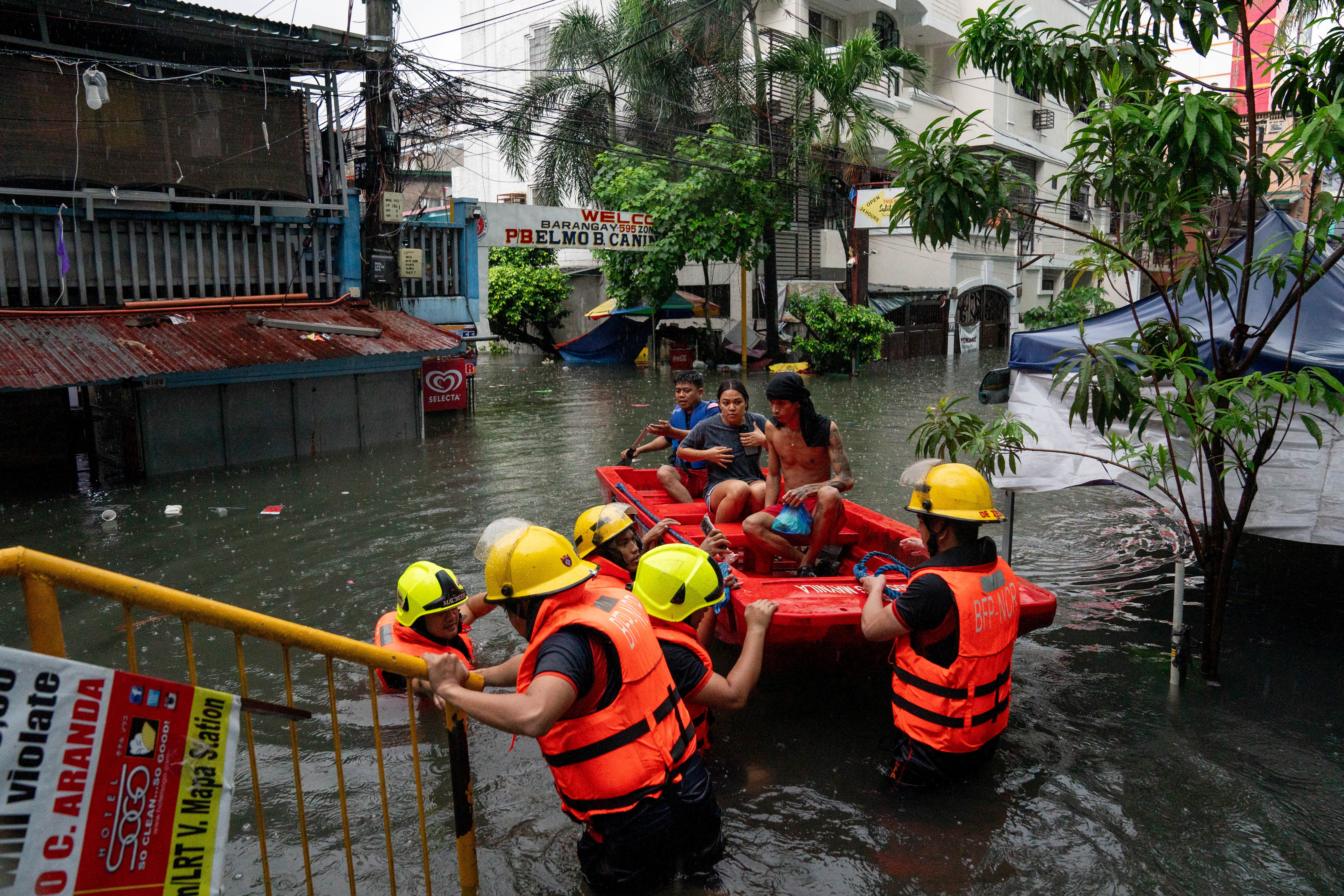 Rescuers assist residents along a flooded street amid heavy rains brought by Typhoon Gaemi, in Manila, July 24
