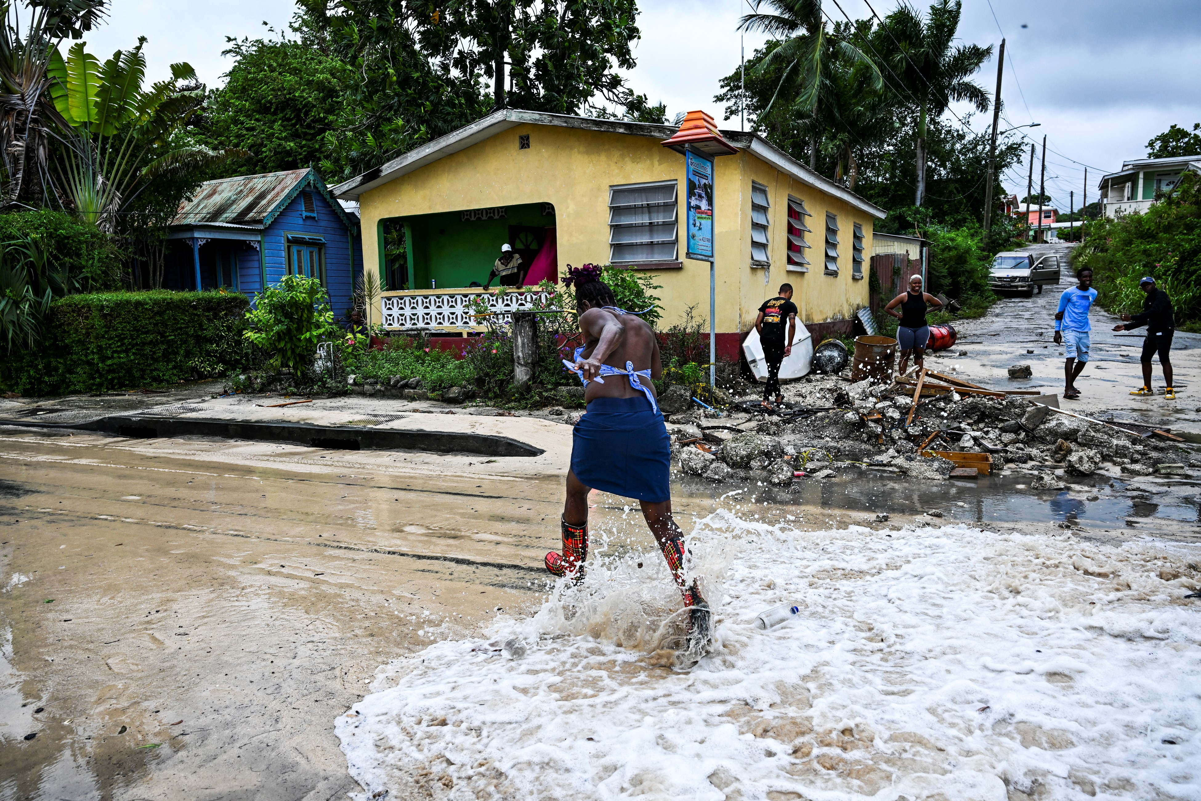A woman runs to avoid incoming sea water on a street in St James, Barbados