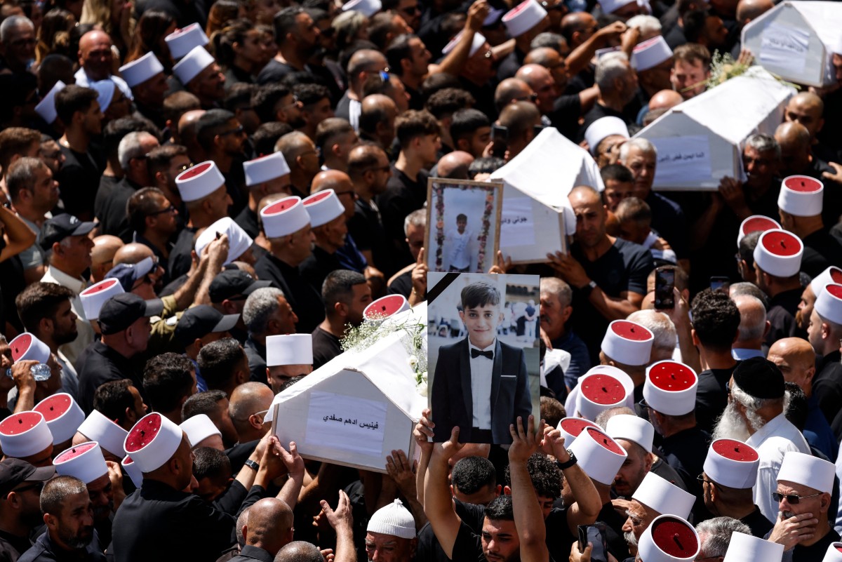 Mourners carry coffins and pictures of people killed on Saturday, July 27 during a mass funeral in the Druze town of Majdal Shams in the Israel-annexed Golan Heights, on Sunday, July 28, 2024