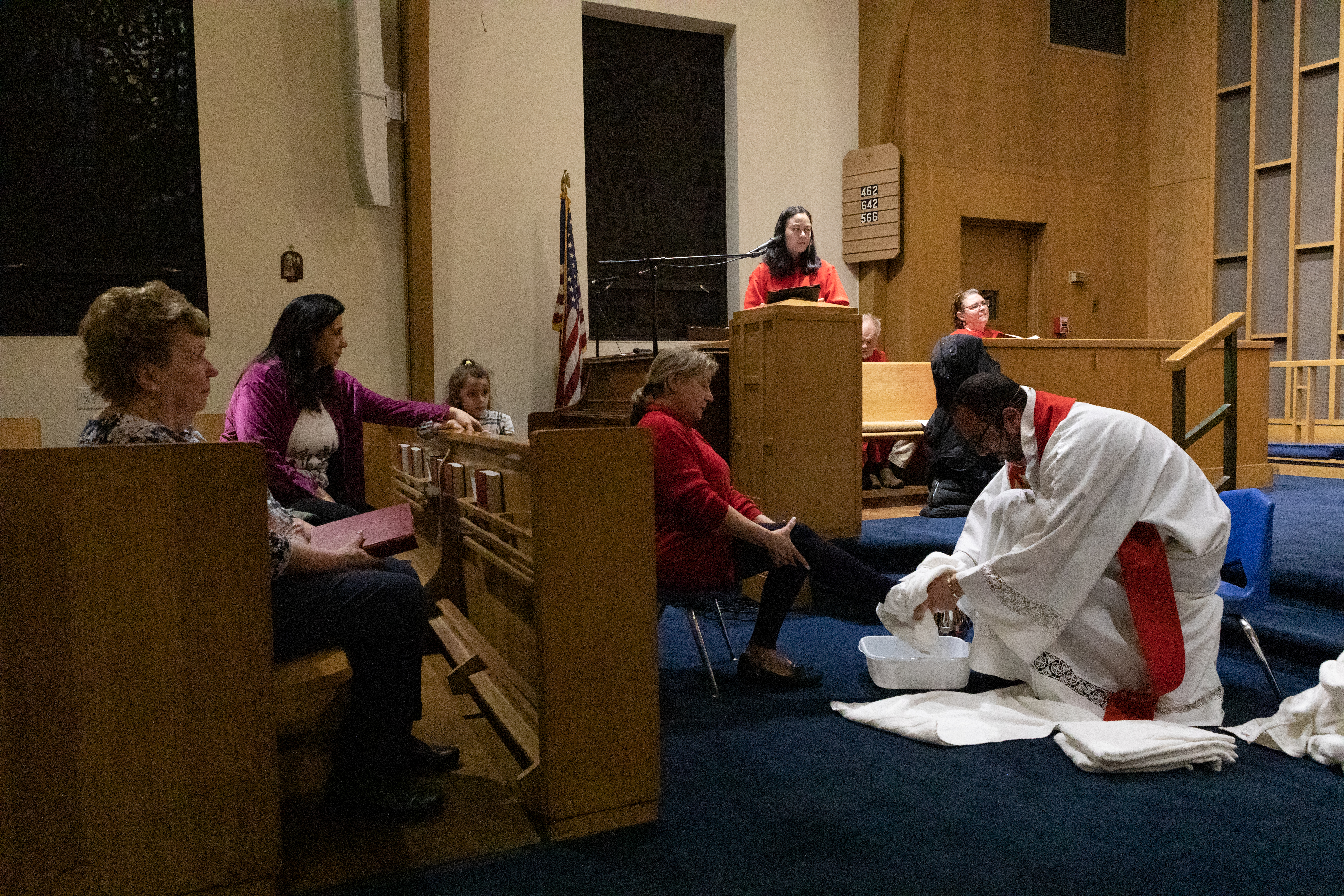 Pastor Khalilia kneels in his white robes to wash the feet of a parishioner at the front of the church.
