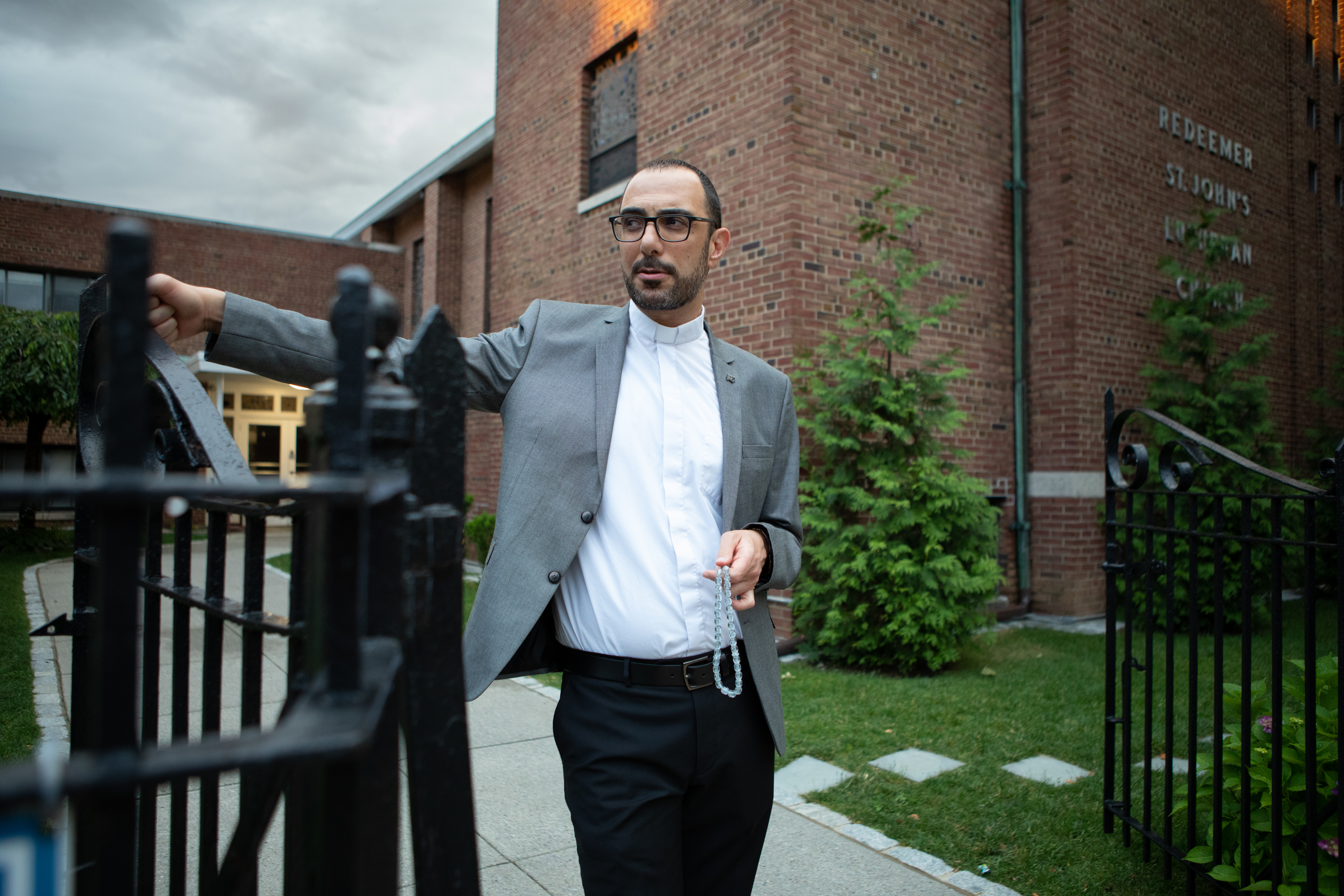Dressed in a grey blazer and a high-collar preacher's shirt, Pastor Khalilia opens the wrought-iron gate to his red-brick church. He holds prayer beads in one hand.