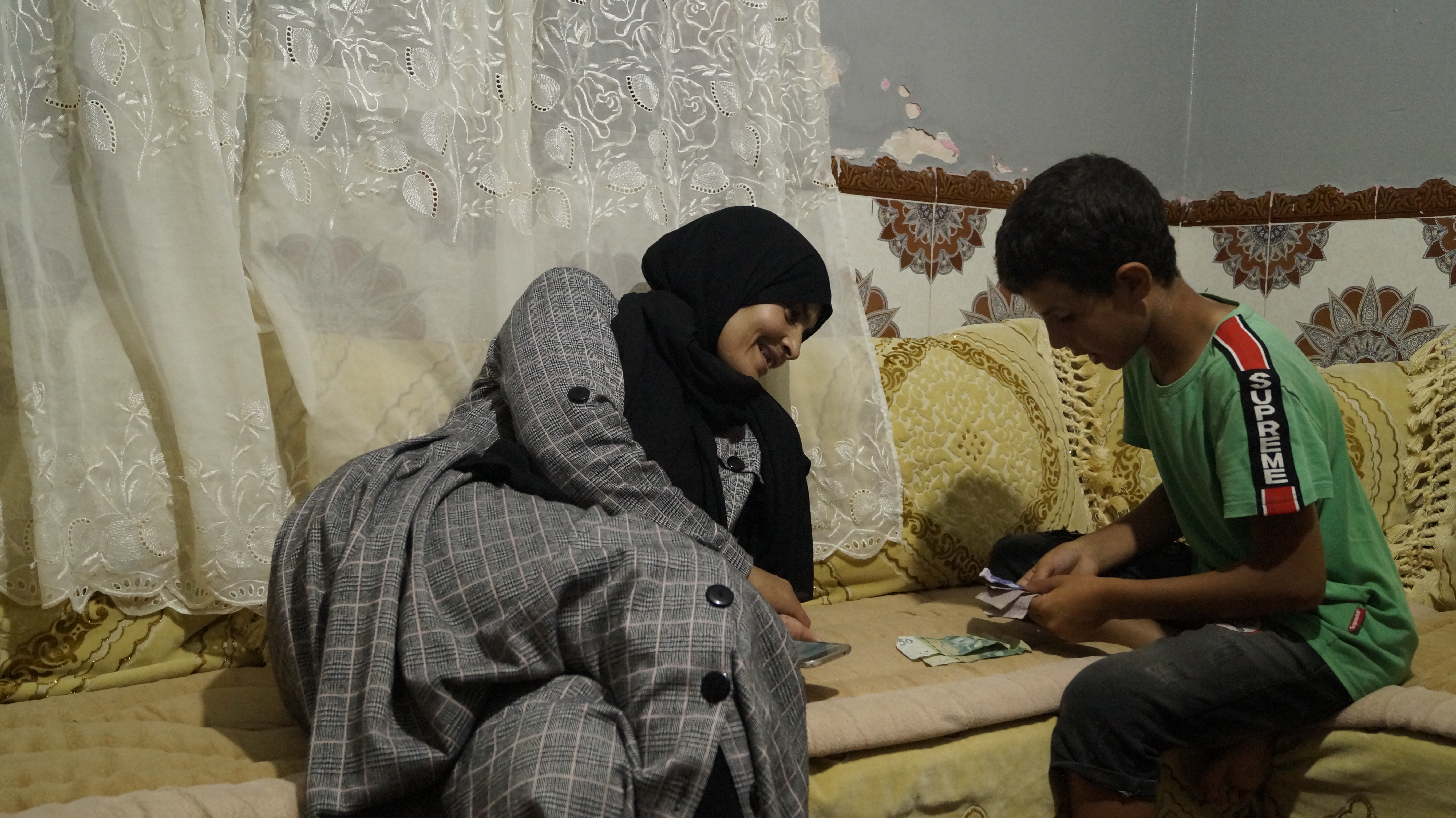 Ilyas’s brother, Zakarya, 12, helps his mother count the money she has earned during the day. Aseya is terrified she will come home from work one day to find Zakarya has gone, as well