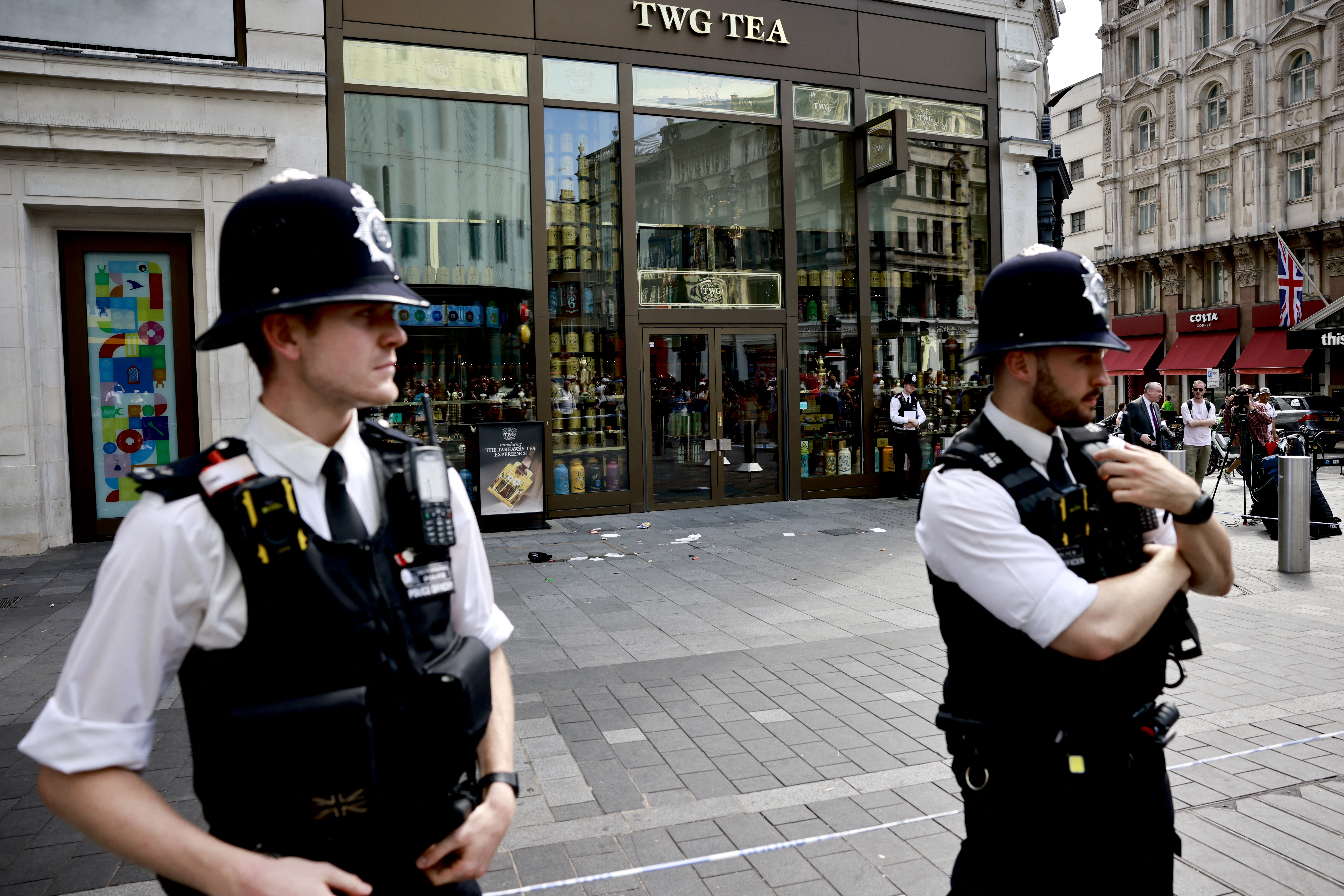 A photograph taken on August 12, 2024 shows police officers standing by a cordoned off area in Leicester square, London. - A woman and an 11-year-old girl were hospitalised on August 12 after being stabbed in central London's famous Leicester Square, police said, adding that a man had been arrested. (Photo by BENJAMIN CREMEL / AFP)