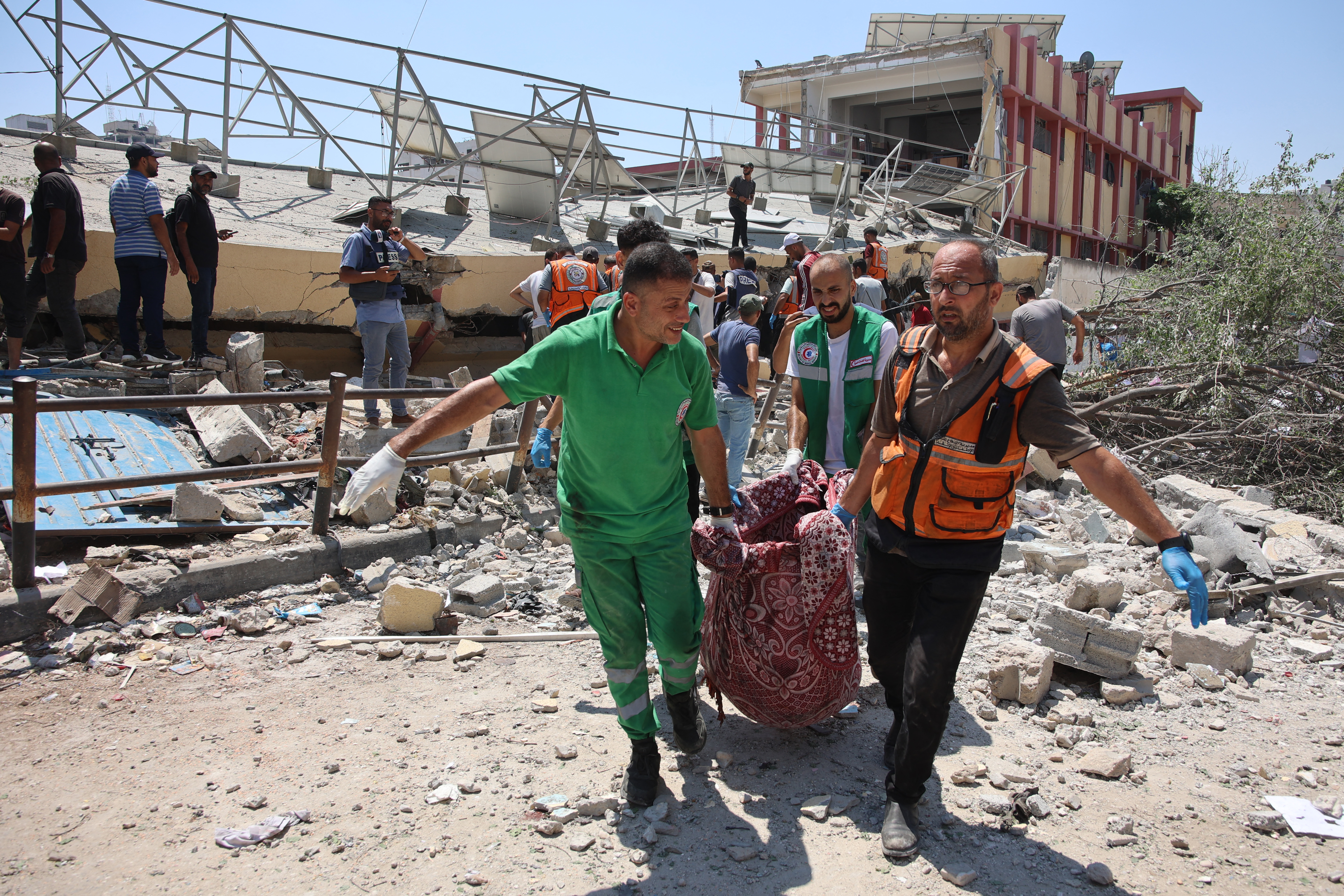 Paramedics carry a body from the site of an Israeli strike on a school, housing displaced Palestinians, in the Rimal neighbourhood of central Gaza City on August 20, 2024, amid the ongoing conflict between Israel and the militant Hamas group. (Photo by Omar AL-QATTAA / AFP)