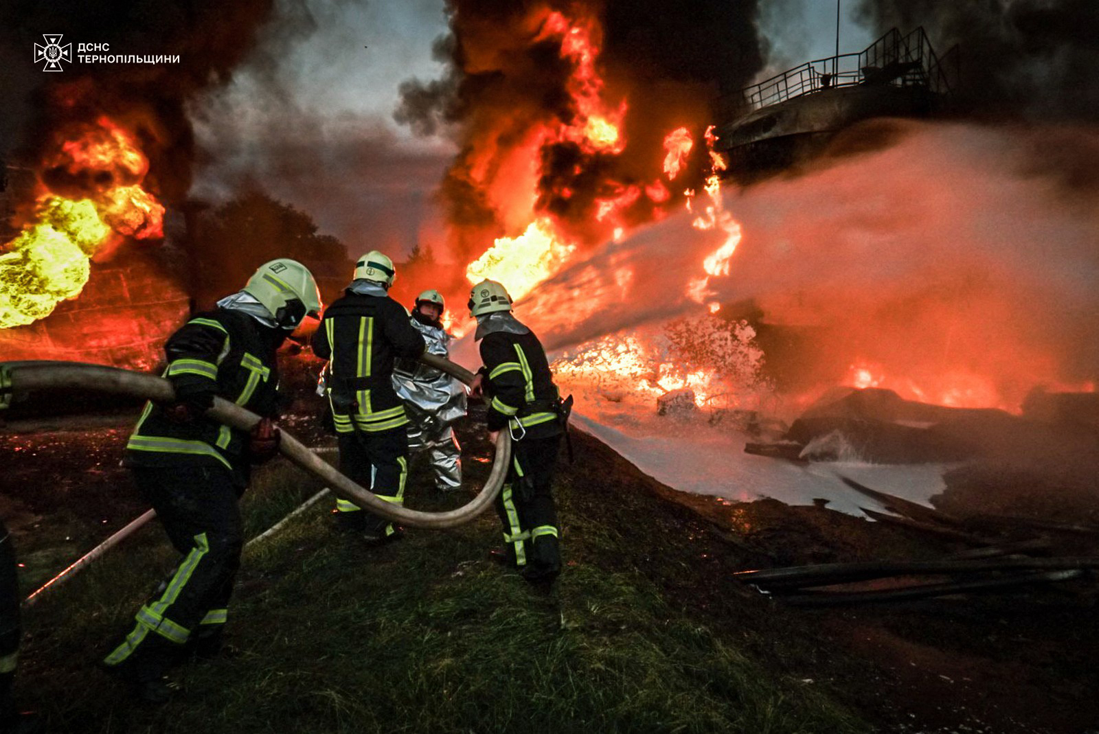 Firefighters battling a large fire. They are directing their hoses at the flames.