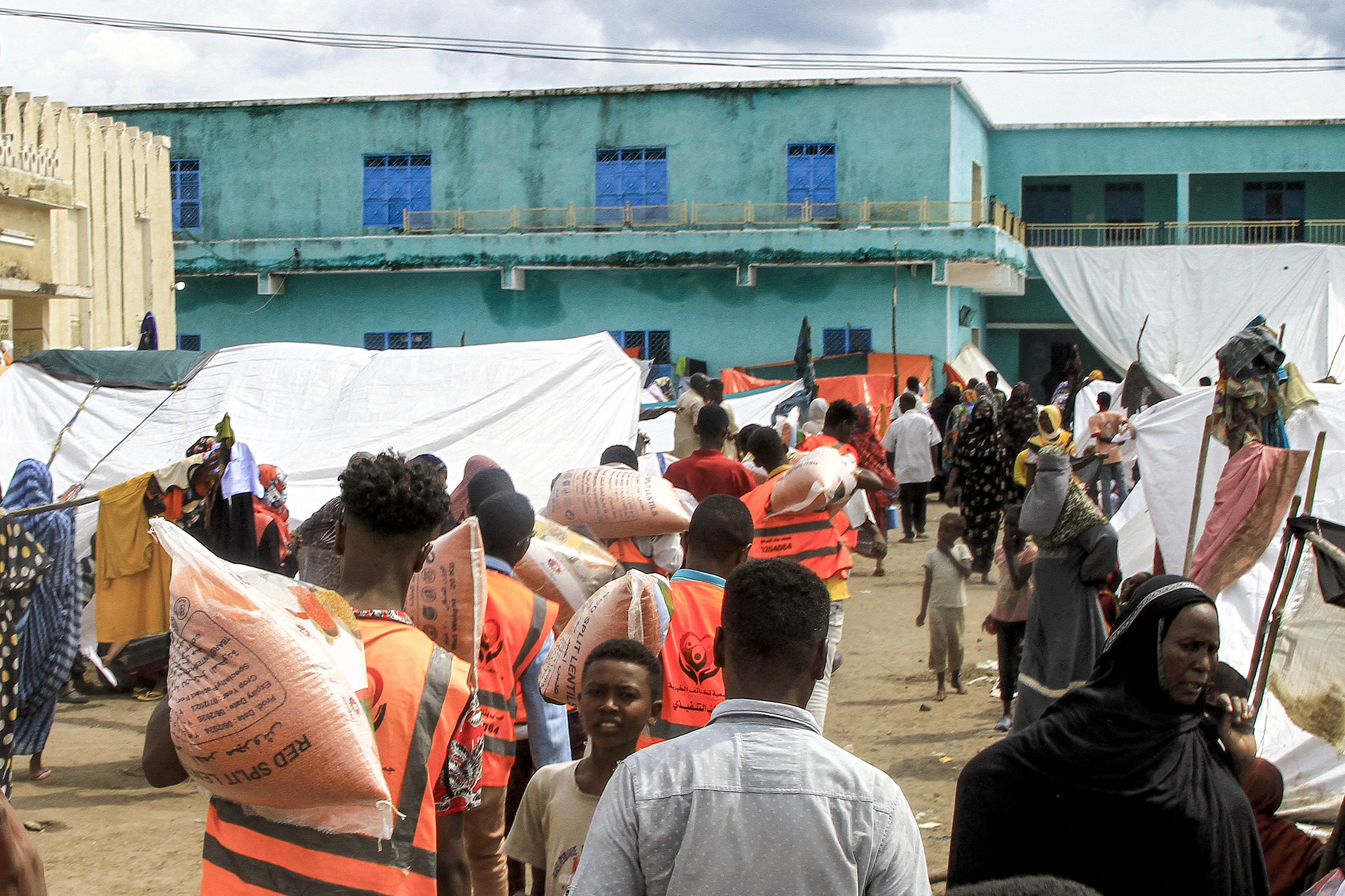 Members of a charity transport sacks of lentils being provided as food aid to people displaced by conflict at a shelter in Sudan’s eastern city of Gadarif