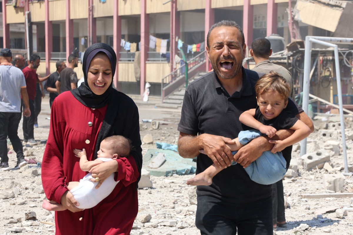 Palestinians carry their children as they flee an Israeli attack on a school in Gaza City