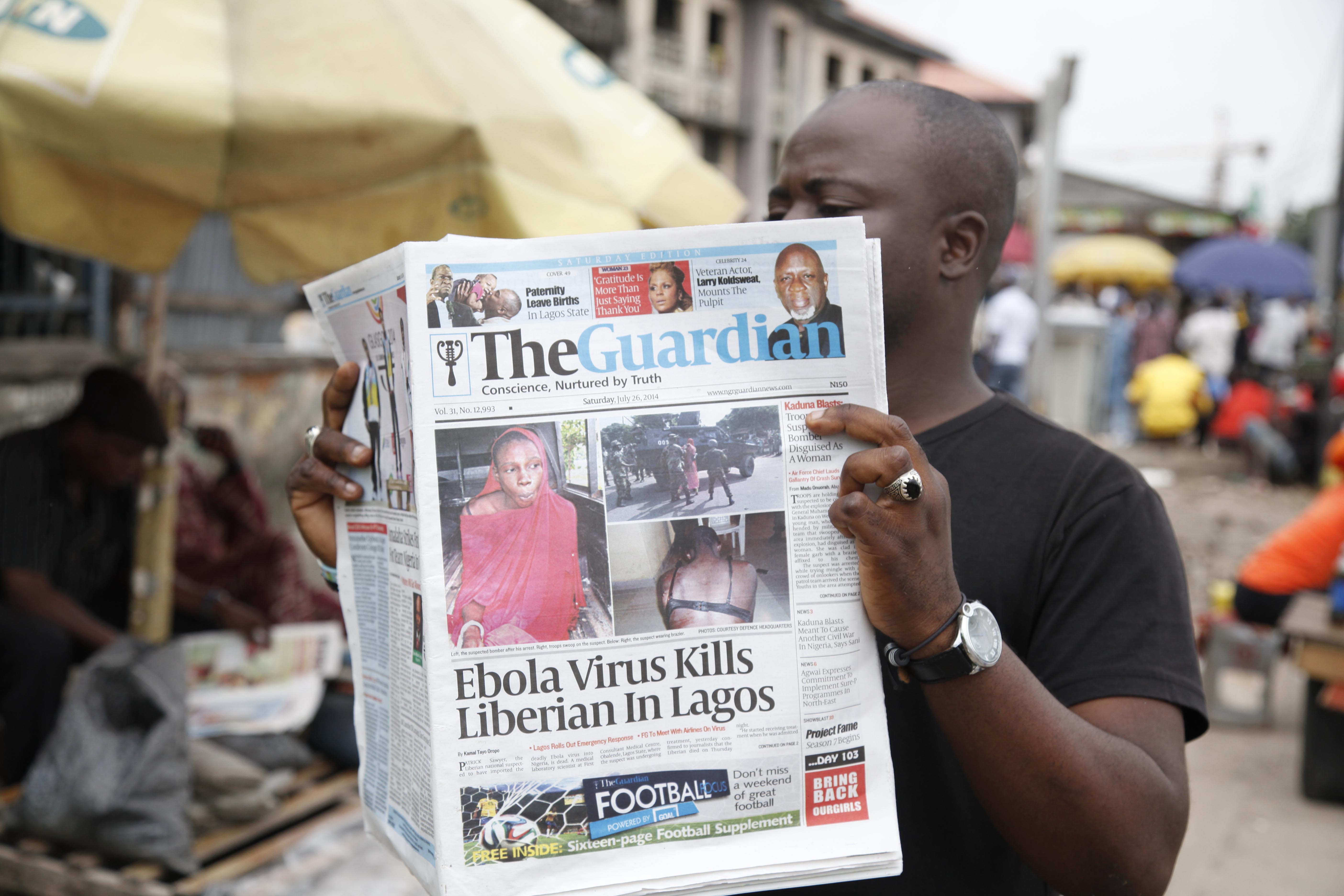 A man reads a newspaper on a Lagos street during an outbreak of Ebola in West Africa in 2014