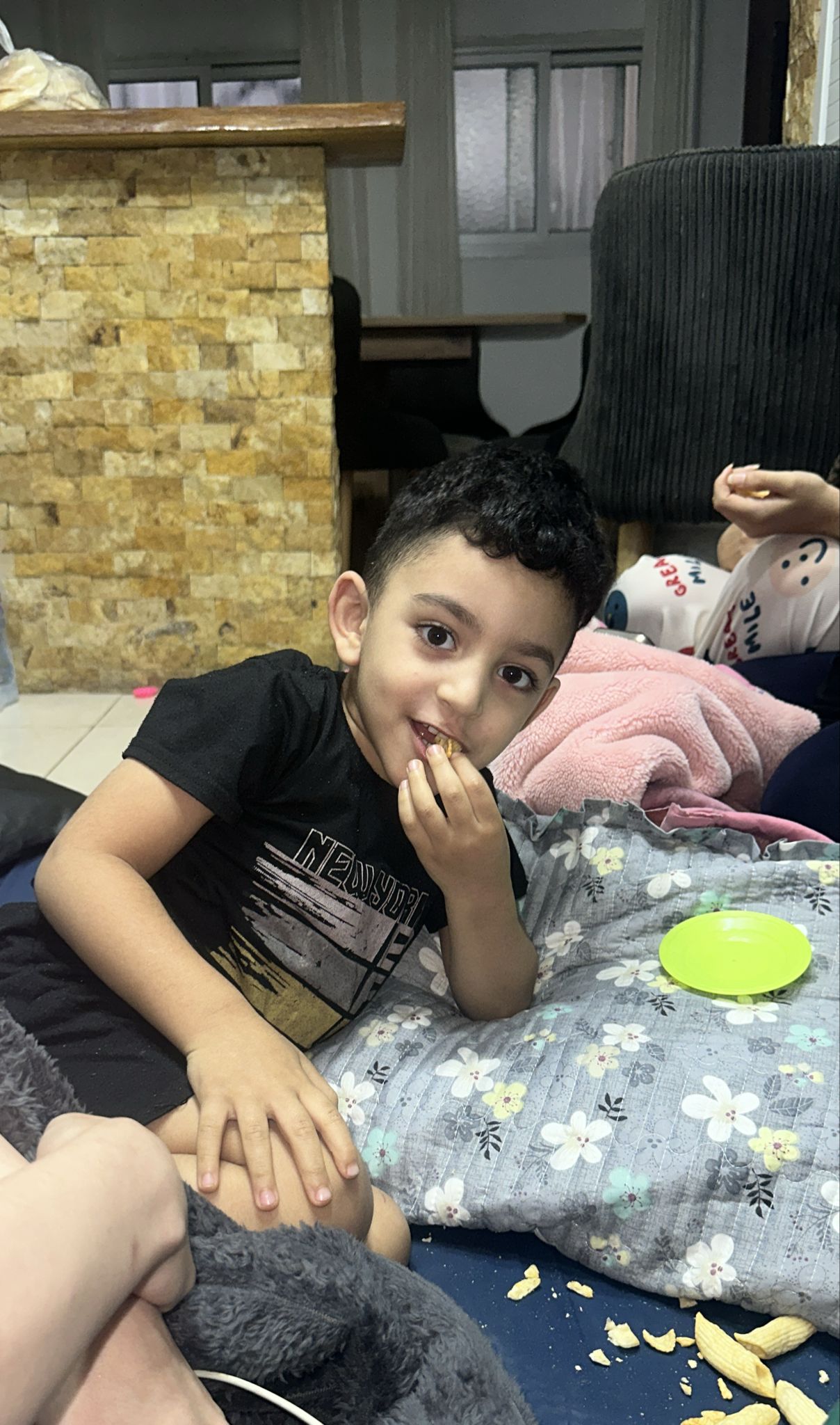 Saja’s nephew, Jawad, eats crisps as he lays on a mattress in the family home’s kitchen [Courtsey of Saja Bawaqneh]