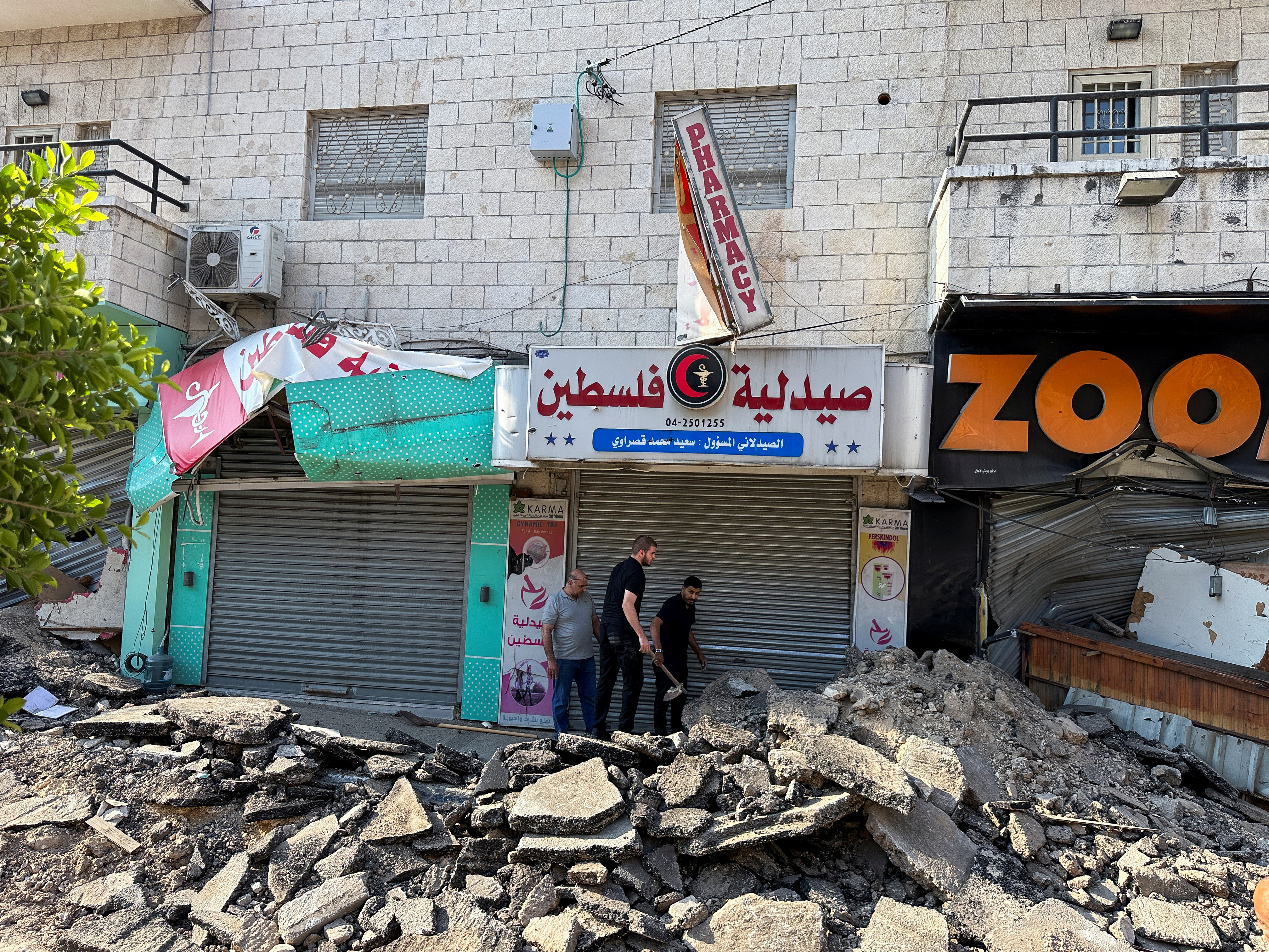 Palestinians assess damage in the street following an Israeli military operation in Jenin