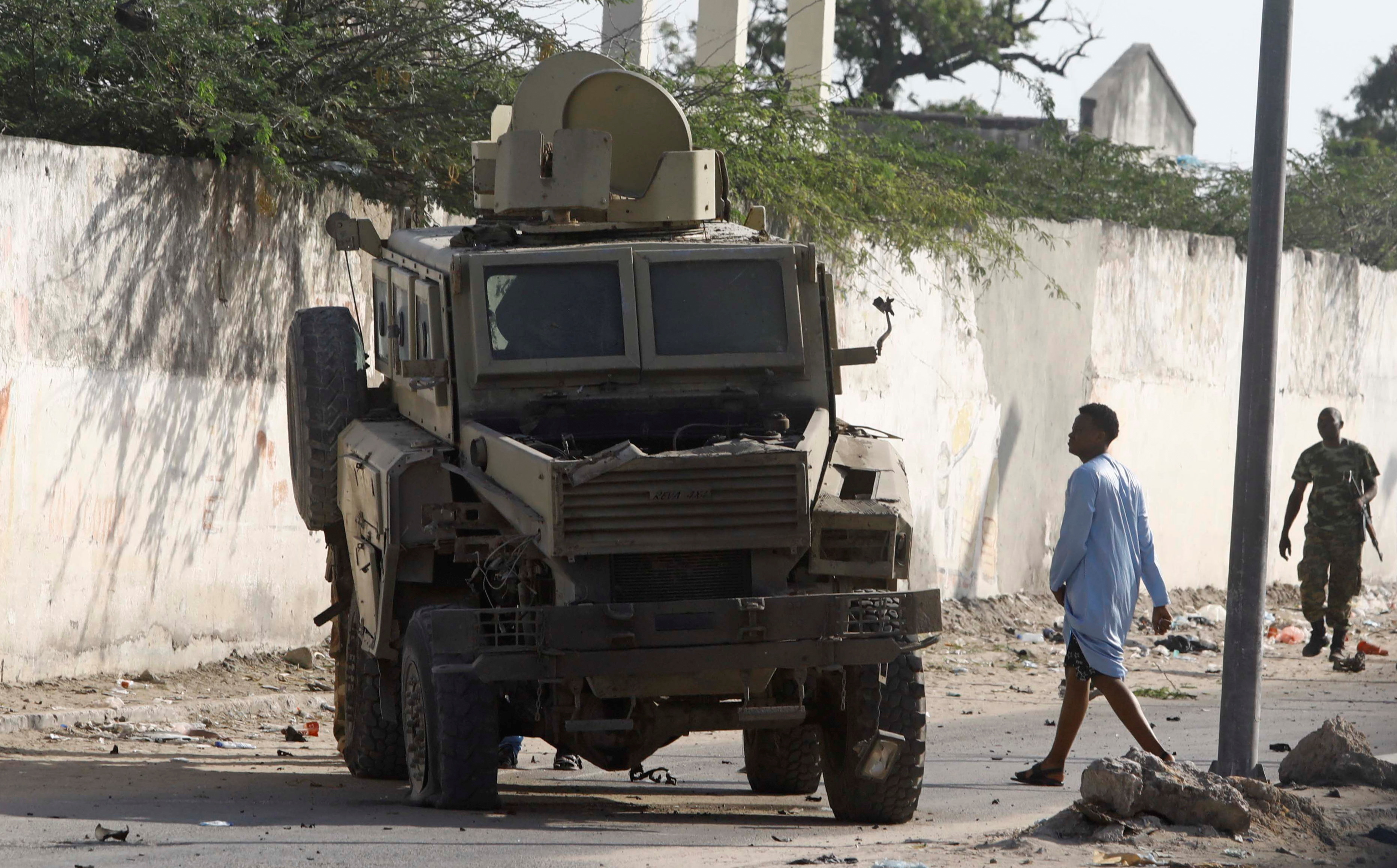 A civilian looks at a destroyed armoured personnel carrier