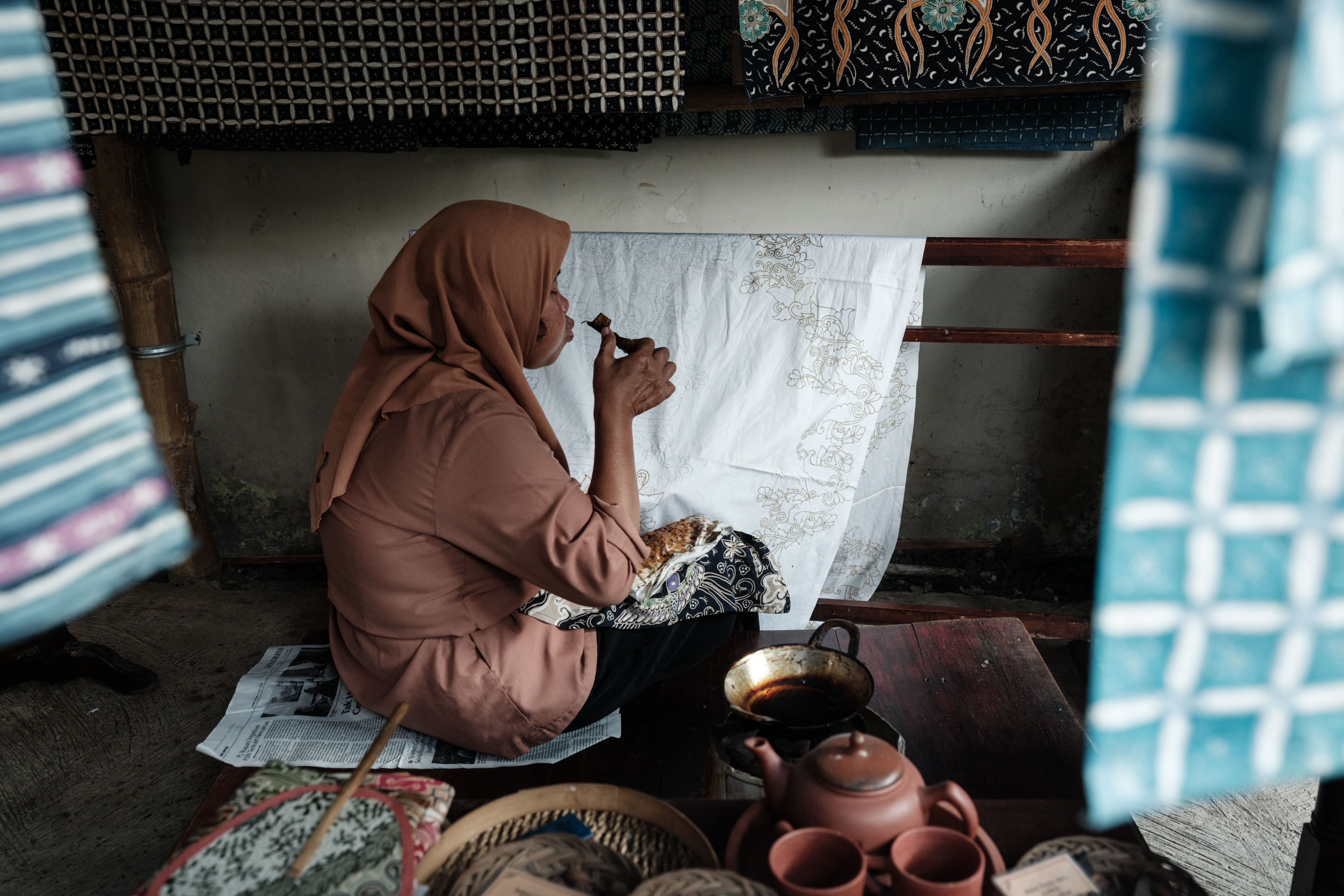 A craftswoman makes traditional batik using a tool with melted wax to draw patterns on fabric at a local batik shop in Surakarta, Central Java, on July 30, 2024