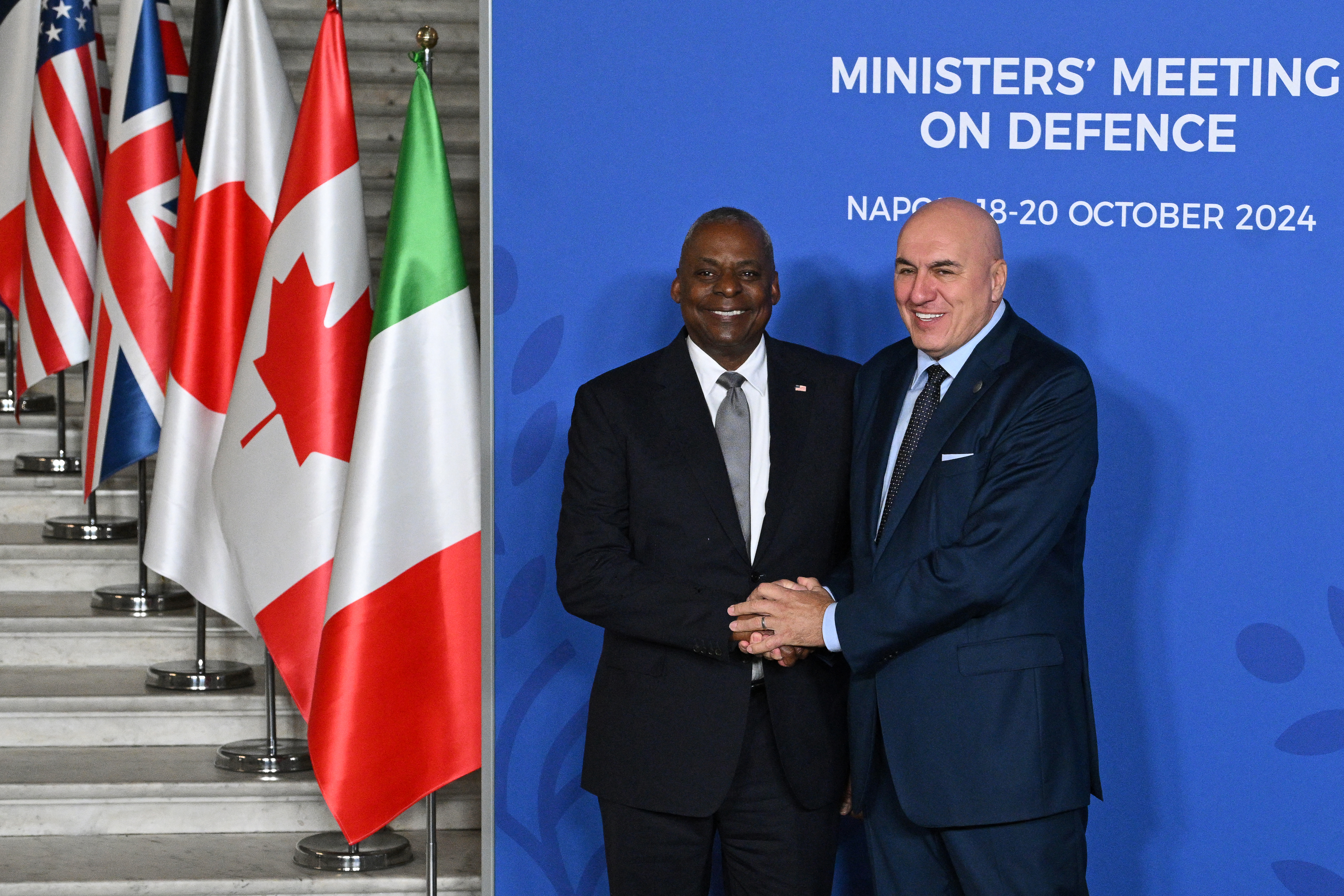 Italy's Defense Minister Guido Crosetto (R) and US Secretary of Defense Lloyd Austin shake hands during the welcome ceremony of the Group of Seven (G7) Defence Ministers Summit at the Palazzo Reale in Naples, Italy, on October 19, 2024. (Photo by Tiziana FABI / AFP)