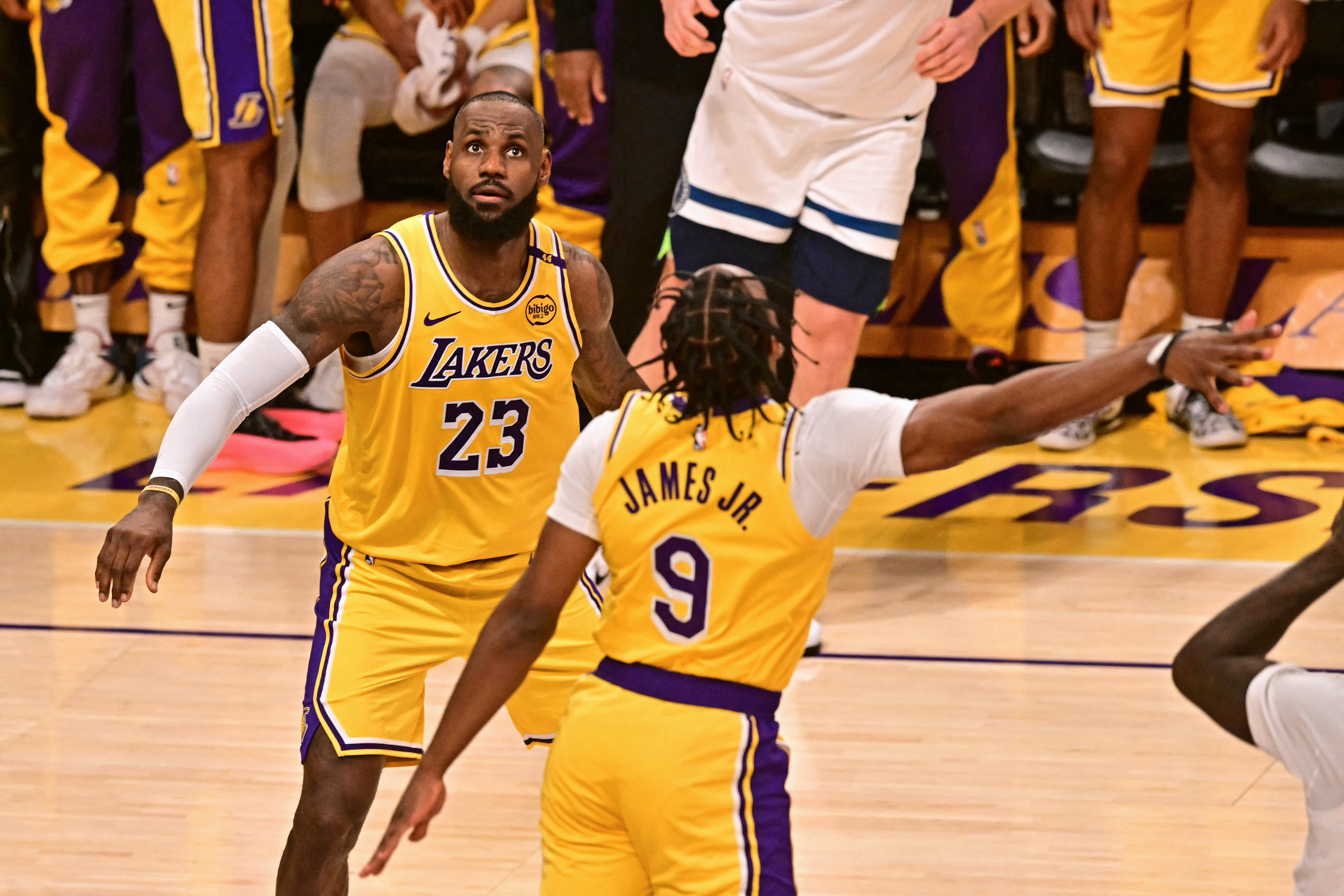 Los Angeles Lakers' US guard #09 Bronny James jumps to block a shot as Los Angeles Lakers' US small forward #23 LeBron James looks on during the NBA game season opener between the Los Angeles Lakers and the Minnesota Timberwolves at Crypto Arena in Los Angeles on October 22, 2024. - LeBron and Bronny are the first father and son to play together in any NBA game. (Photo by Frederic J. Brown / AFP)