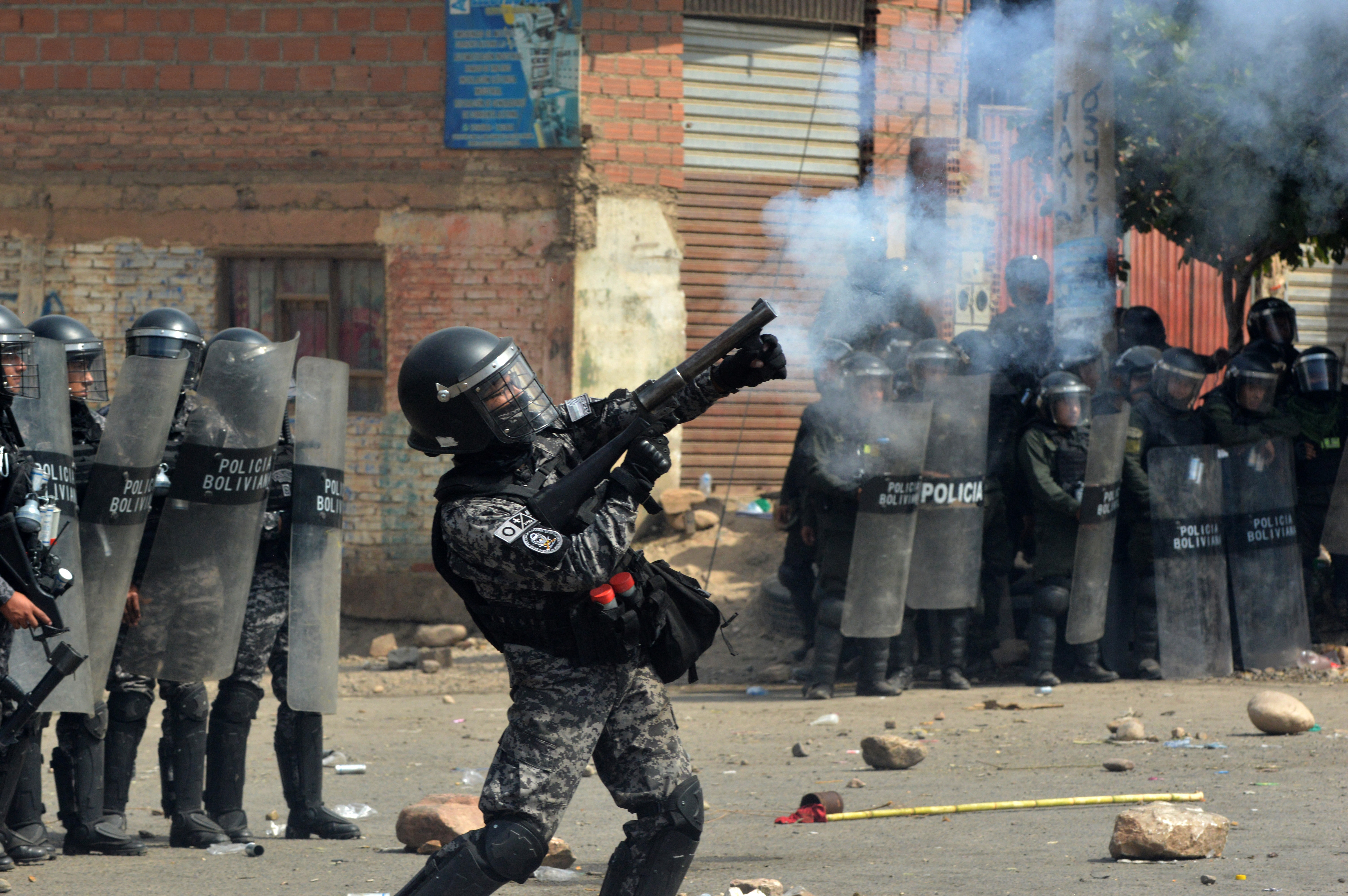 A riot police officer shoots a tear gas can at demonstrators supporting former president Evo Morales during a road blockade in Cochabamba, Bolivia