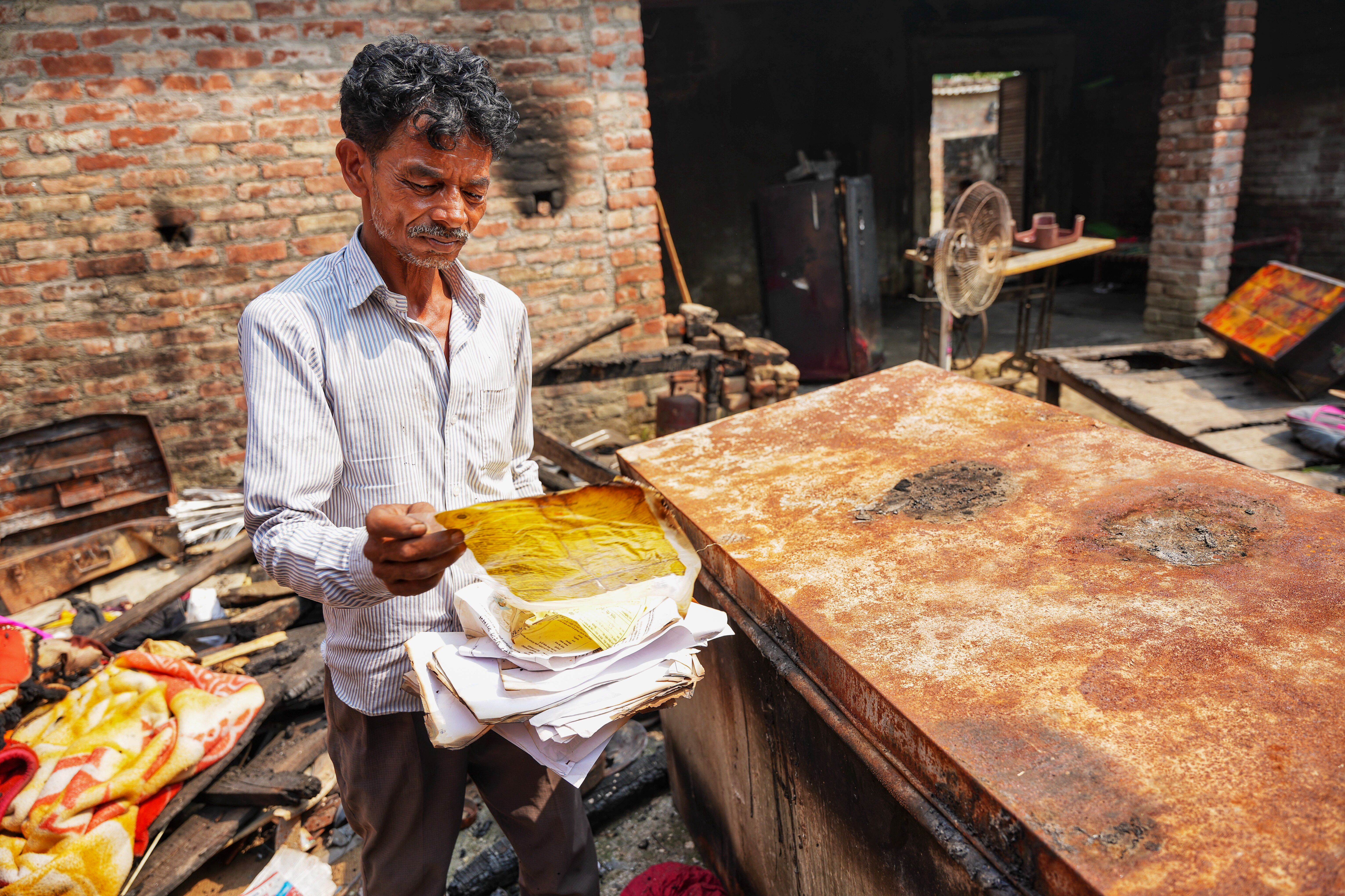 Mangu holding his burned documents at his house in Kapurpur village, Bahraich