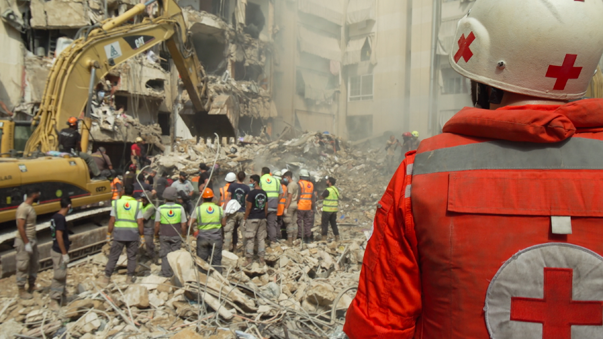 A Red Cross medic looks on as workers sift through the destruction in Dahieh, Beirut, caused by an Israeli strike on September 20 and which killed one Hezbollah commander and 30 civilians