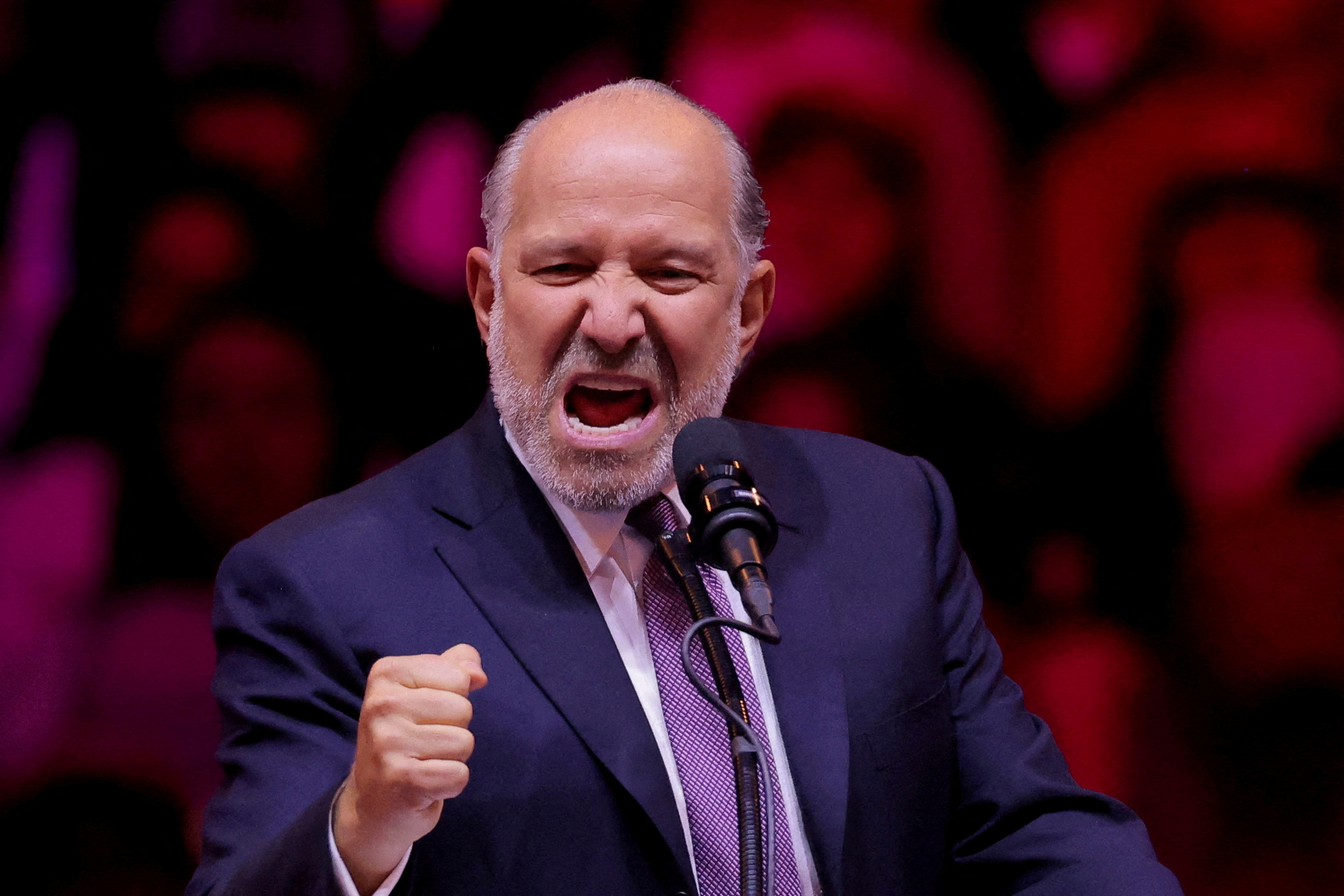 Howard Lutnick pumps his first at a microphone during a Trump rally in New York City