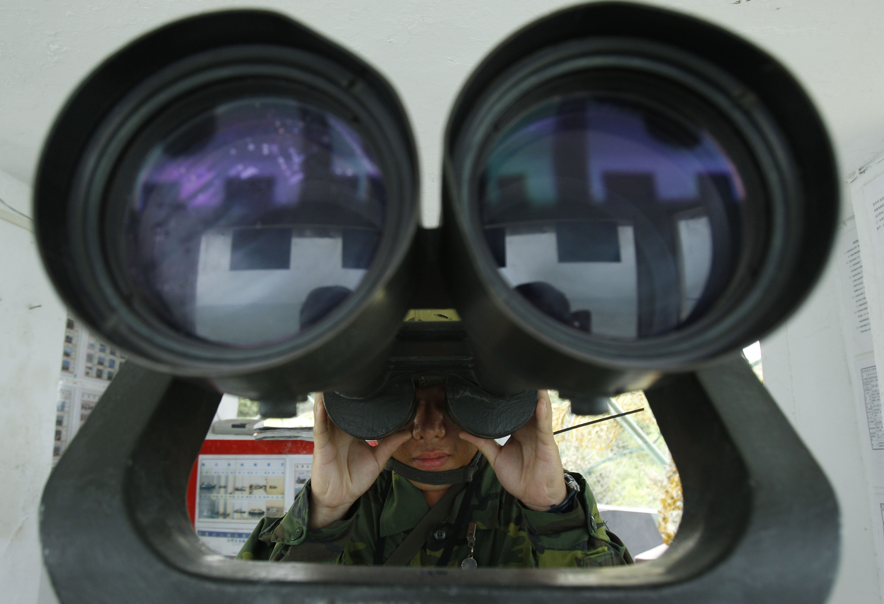 A Taiwanese soldier peers through binoculars towards China just 1.8 kilometers (0.7 miles) from his frontline pillbox on the eve of the 53rd anniversary of a massive bombing campaign on Taiwan's Kinmen island, Taiwan, Monday, Aug. 22, 2011. The Communist government forces on mainland China on August 23, 1958, resumed a massive artillery bombardment on Taiwan's outlying islands of Kinmen (formerly Quemoy) and Matsu, and threatened invasion, the event widely known as the 1958 Taiwan Strait Crisis, which continued until October. (AP Photo/Wally Santana)