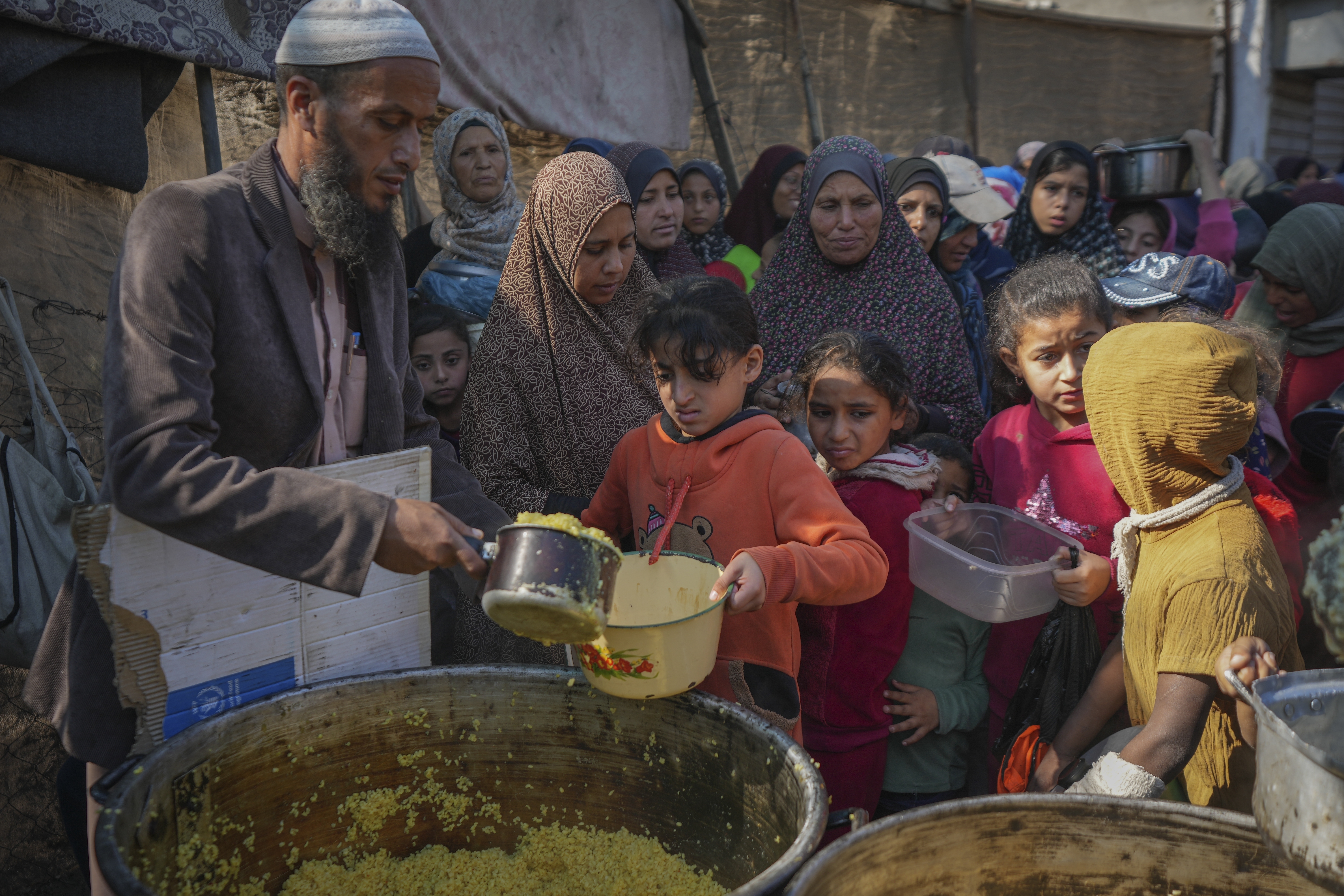 Palestinian children get bulgur wheat at a food distribution kitchen in Deir al-Balah, Gaza Strip