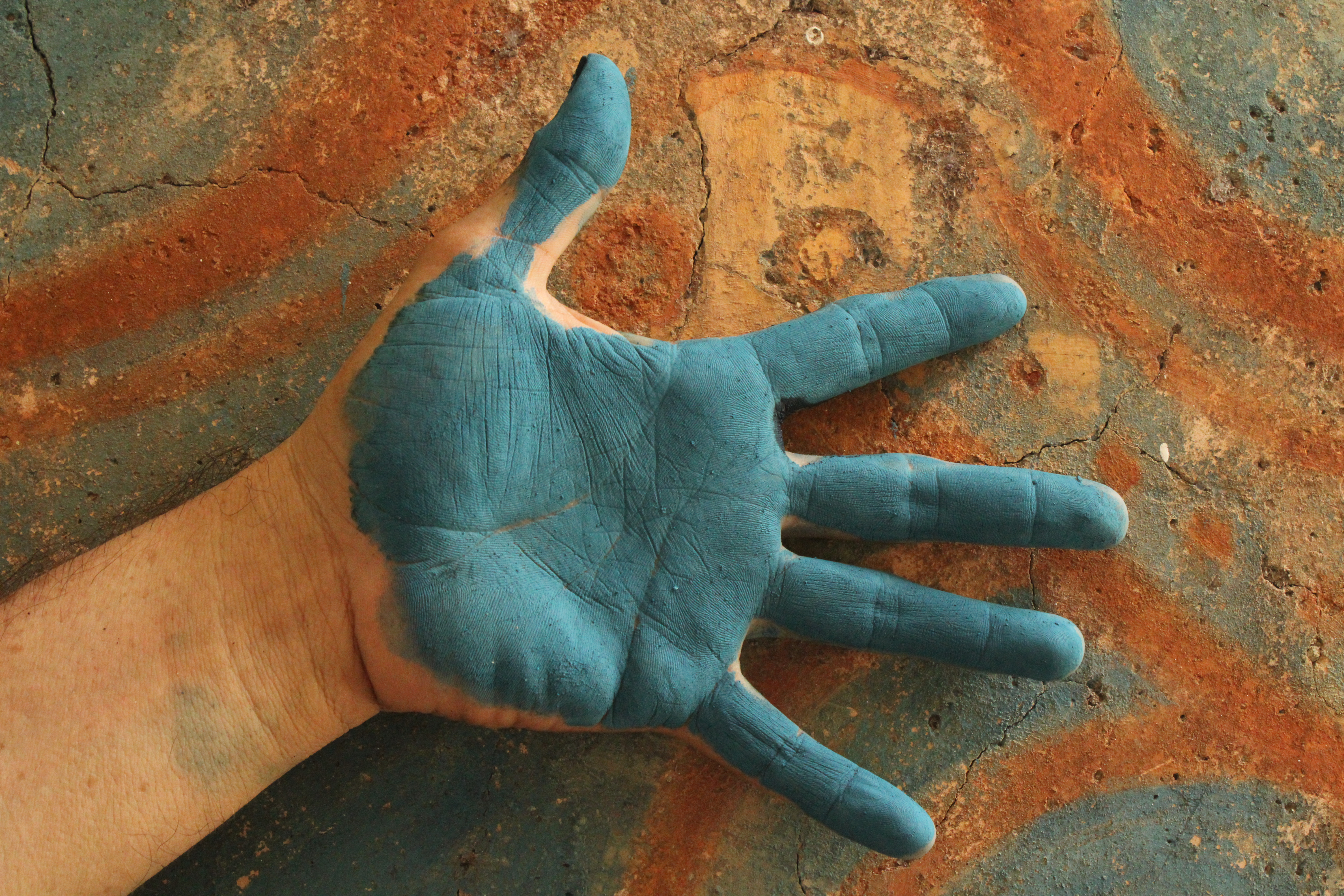 Luis May Ku, 49, places the back of his hand that is painted in Maya Blue against a fire kiln outside his home used to heat the formula that creates the pigment in Dzan, Yucatán, Mexico, on 9 September, 2024_.jpg