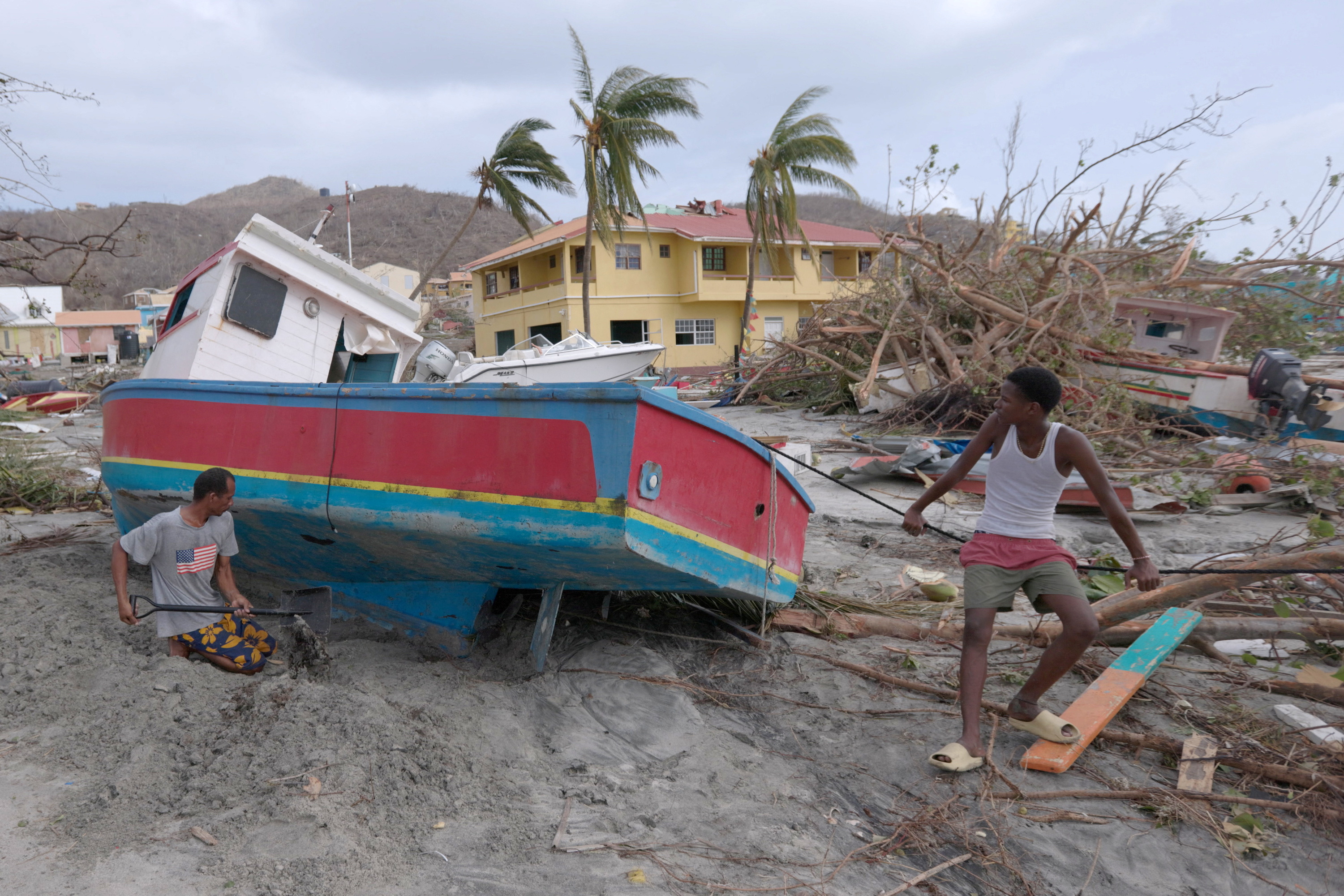 A man digs out a stranded boat after Hurricane Beryl passed the island of Petite Martinique, Grenada July 2, 2024. REUTERS/Arthur Daniel MANDATORY CREDIT