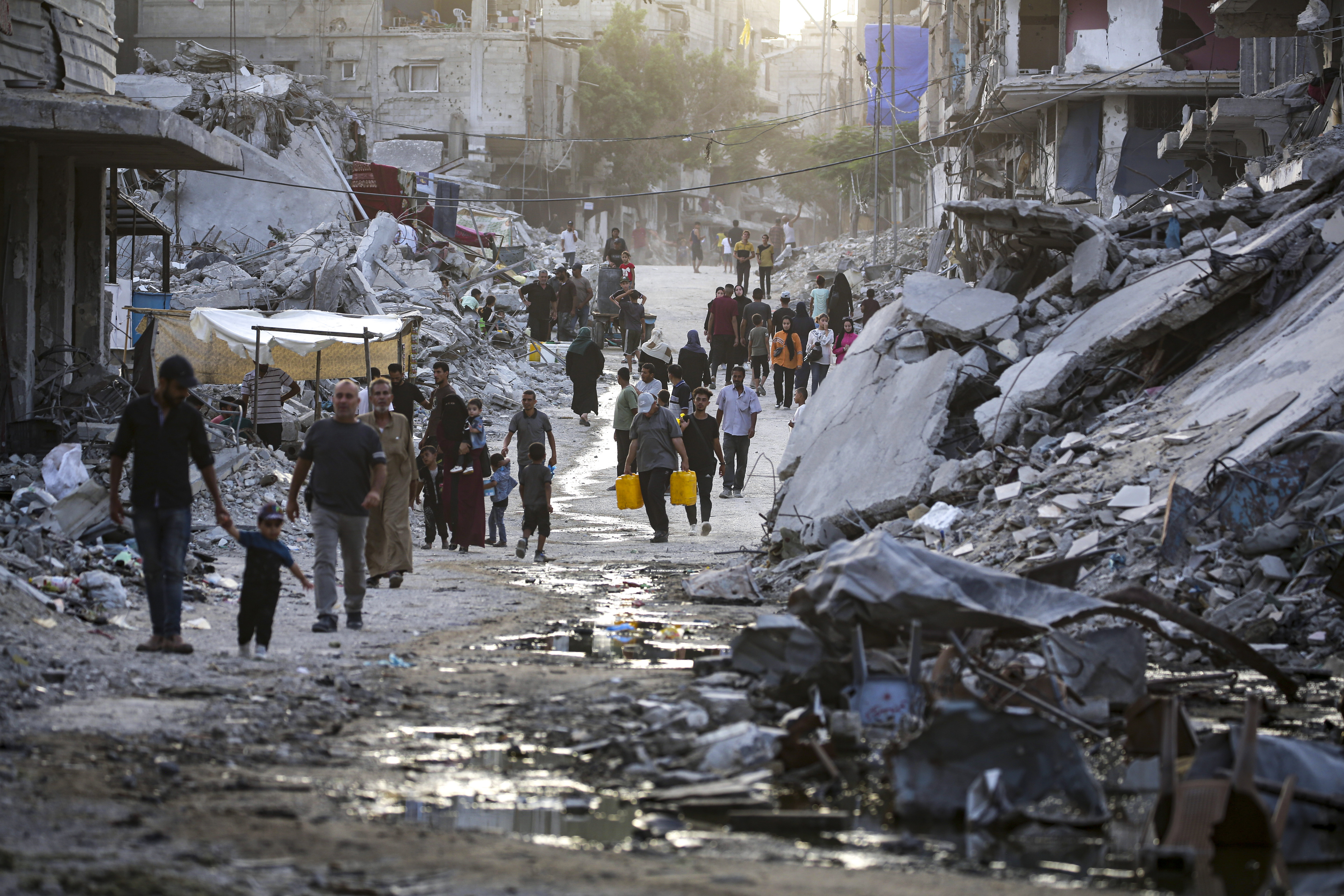 Palestinians displaced by the Israeli air and ground offensive on the Gaza Strip, walk through sewage flowing into the streets of the southern town of Khan Younis, Gaza, on July 4, 2024