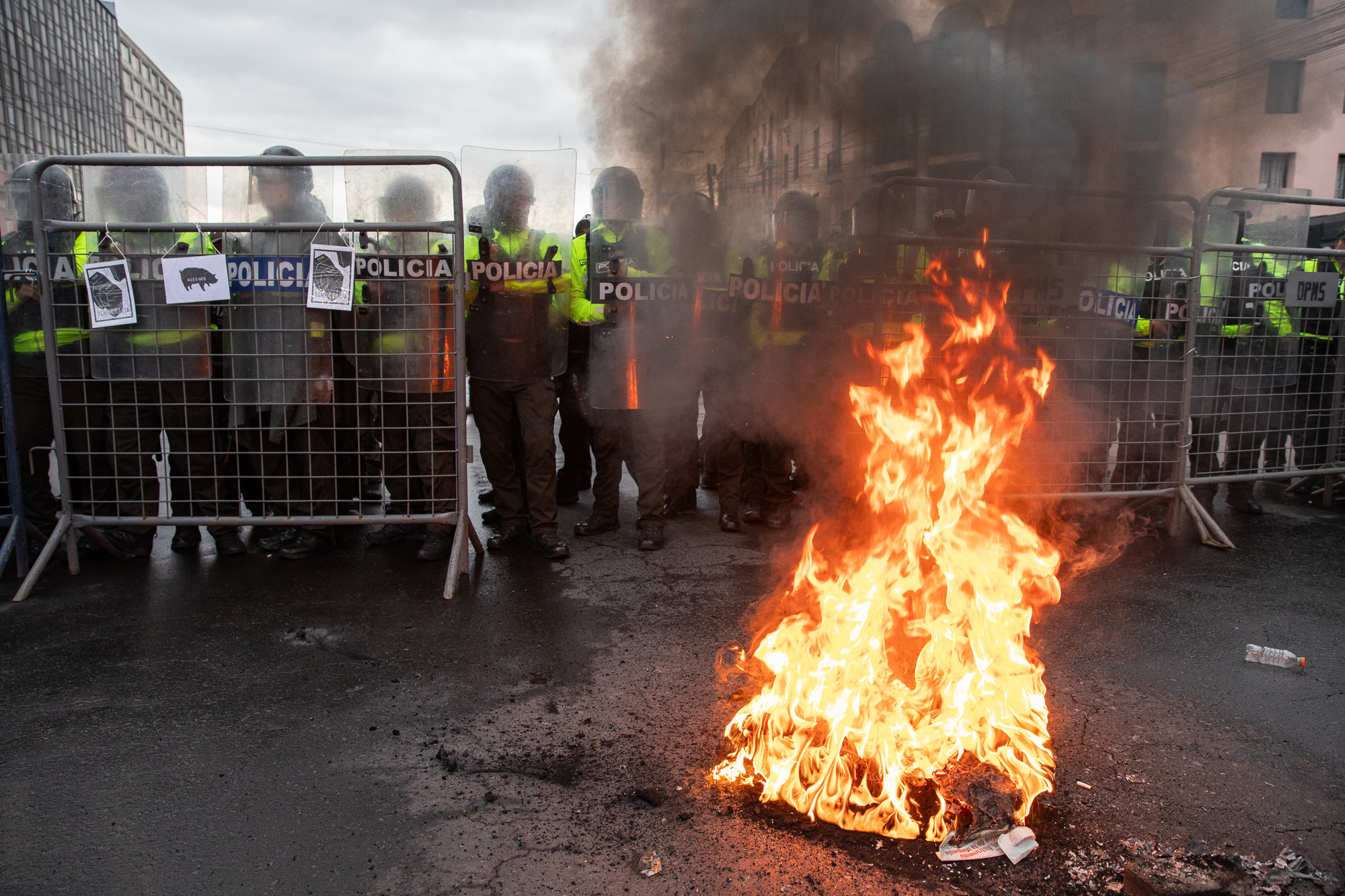 Protesters light a fire in front of a line of police in Quito