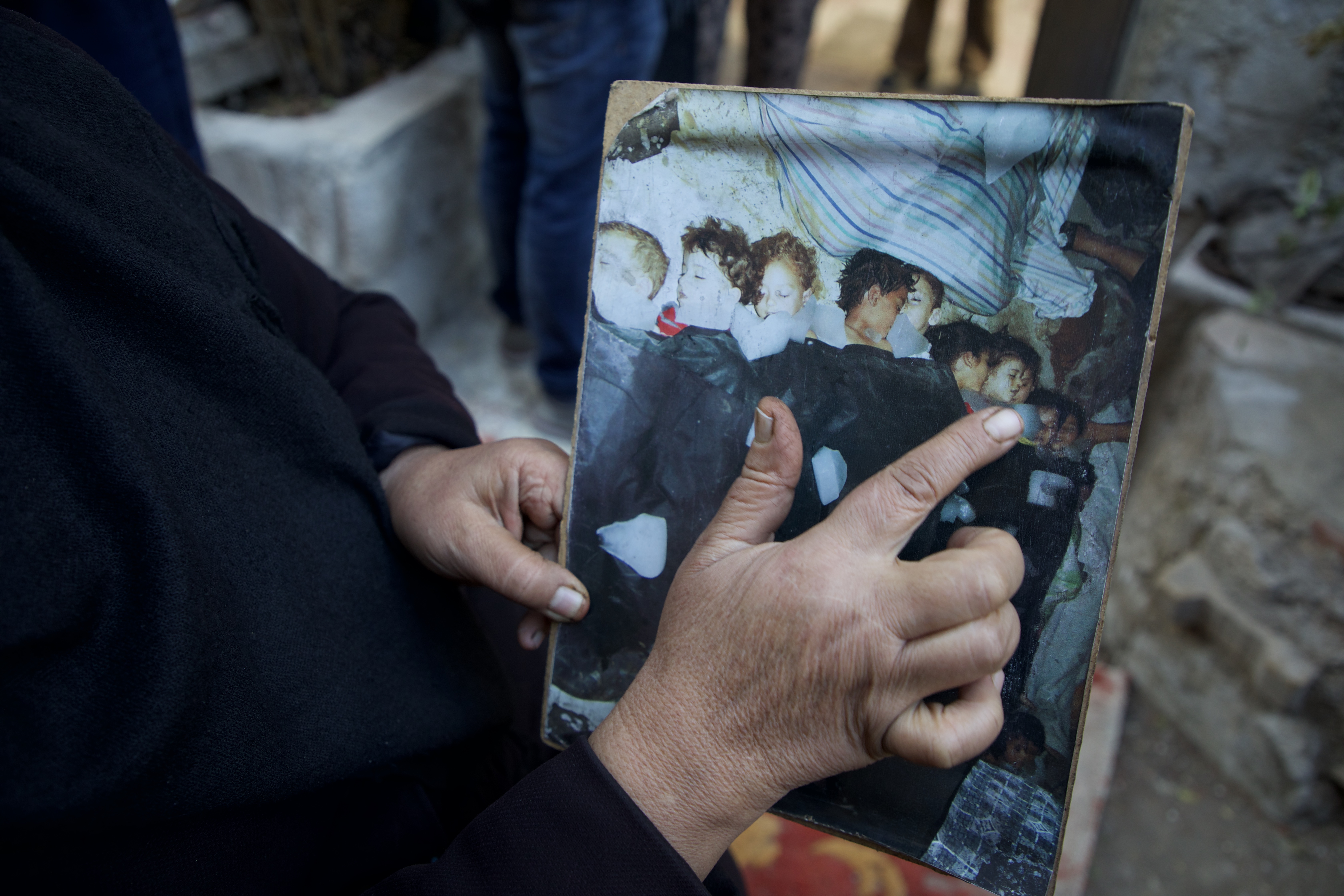 Amina Habya points to one of her grandchildren in the photo that was taken after their bodies were recovered