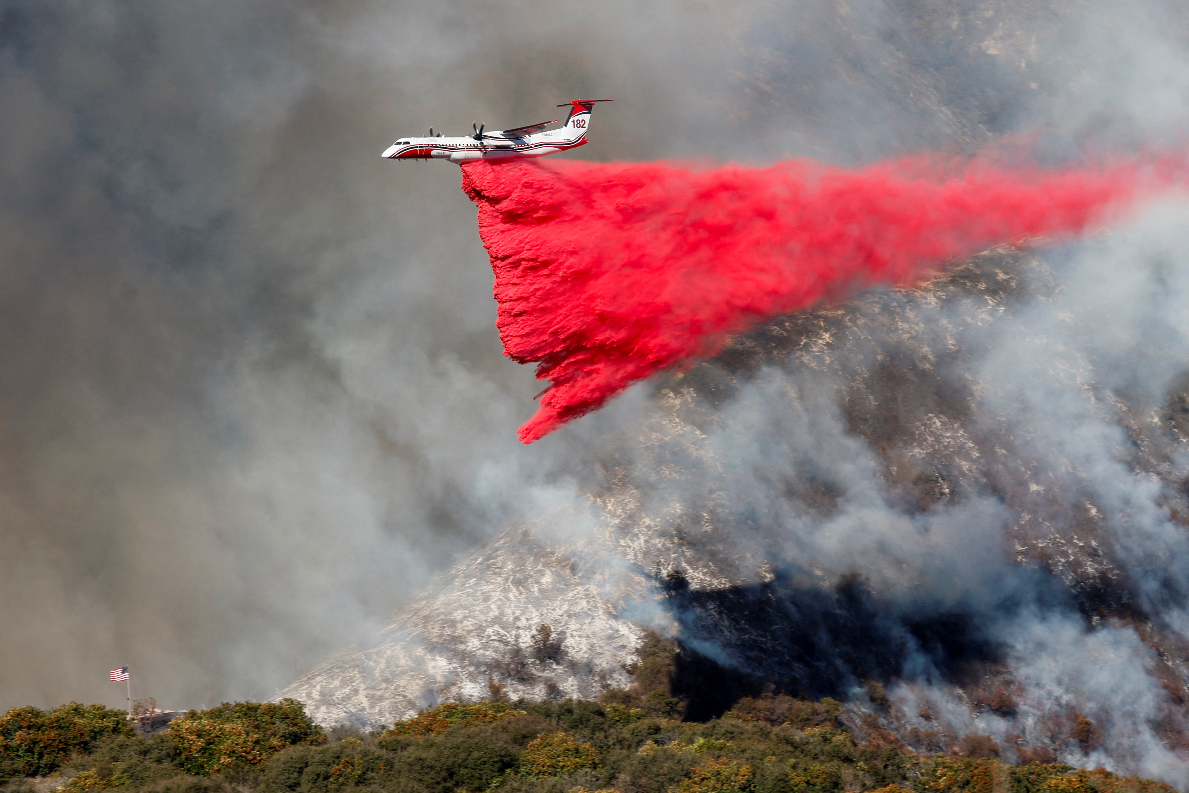 A plane makes a drop as smoke billows from the Palisades Fire at the Mandeville Canyon in Los Angeles