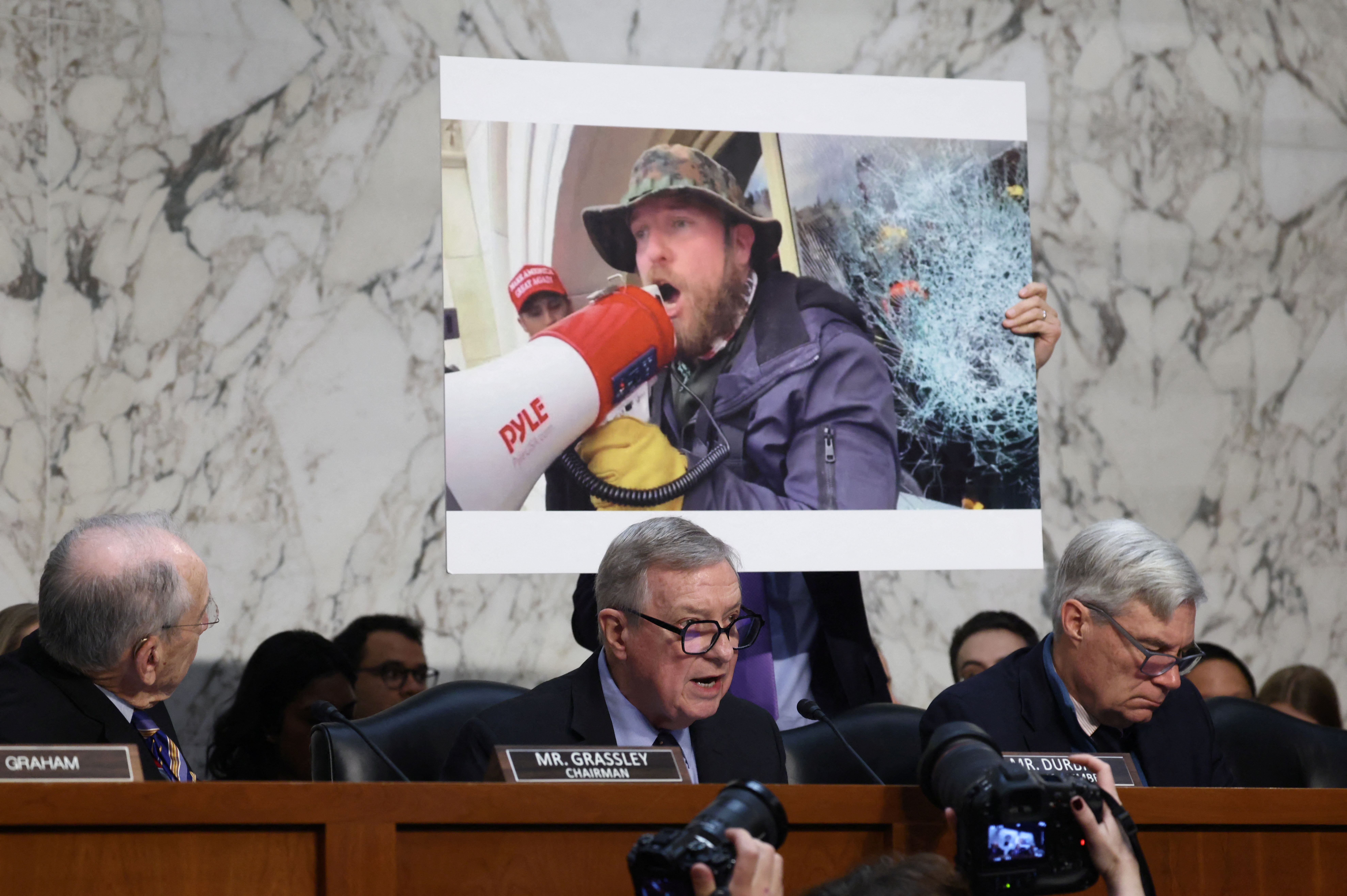 Senator Dick Durbin displays a picture of the US Capitol attack on January 6, 2021, during Patel’s hearing