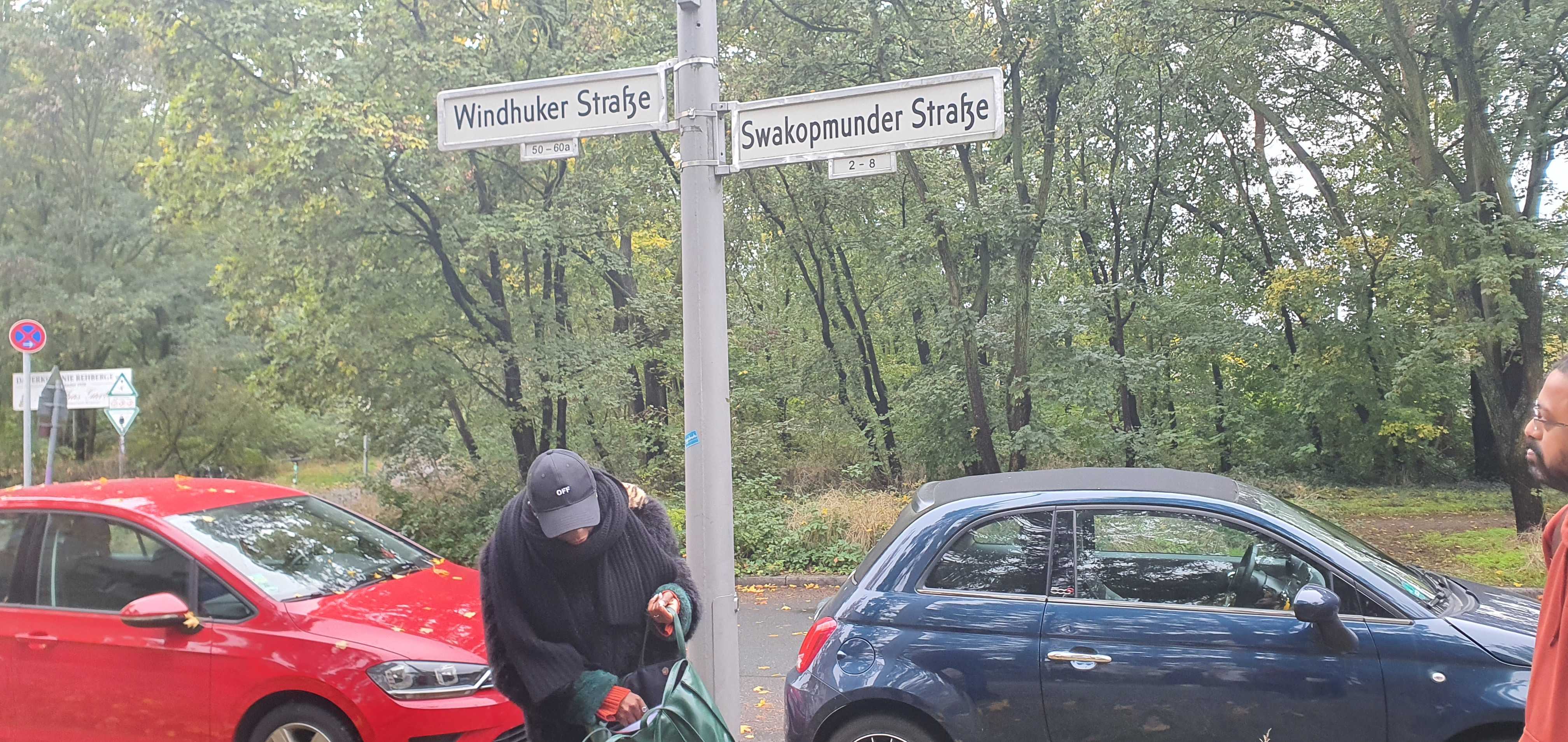 Justice Mfuma Mvemba stands by street signs showing streets named after cities in the former German colony of Namibia