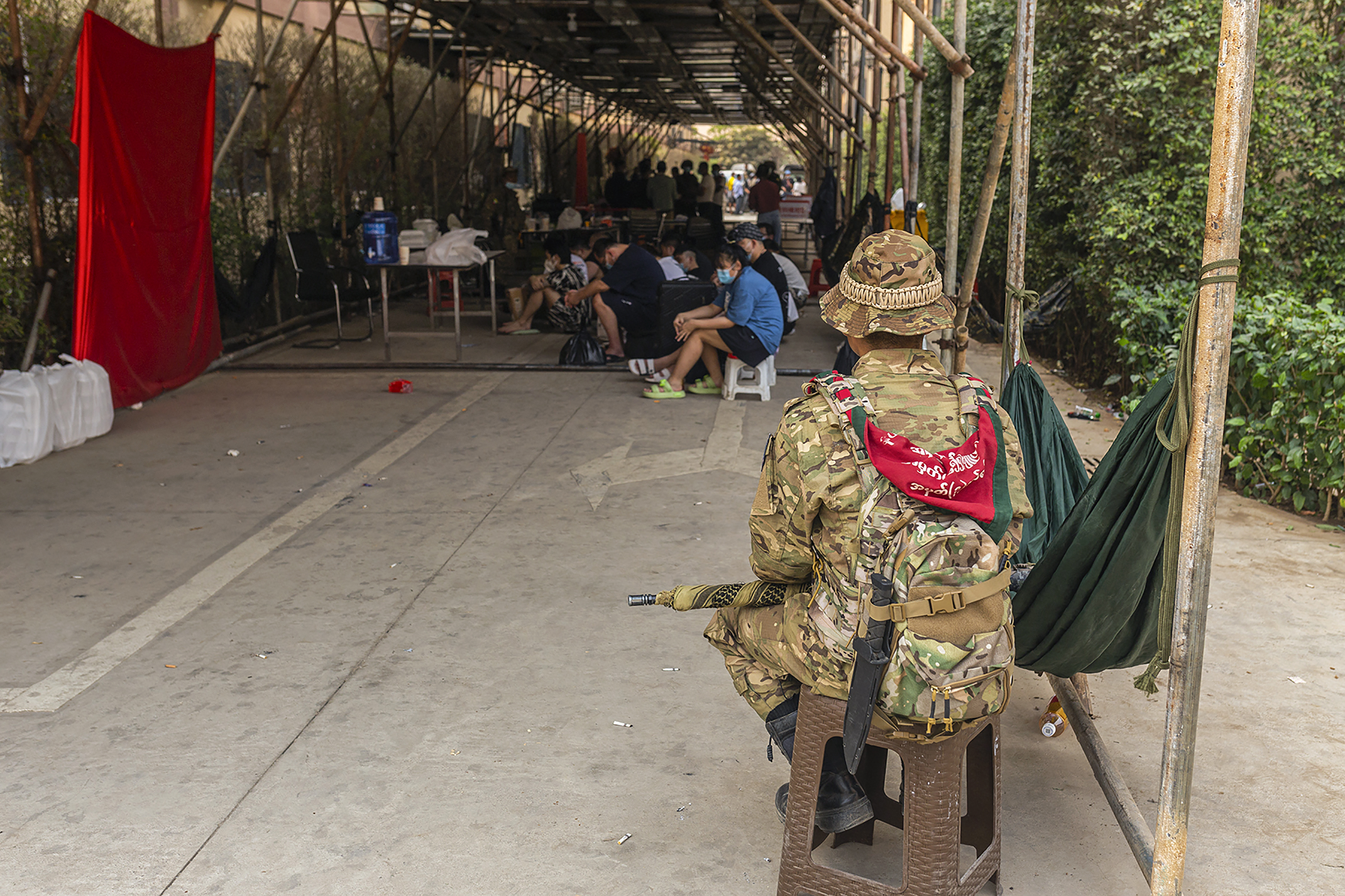 A member of the Karen Border Guard Force (BGF) guards alleged scam centre workers and victims during a BGF crackdown operation on illicit activity in Shwe Kokko in Myanmar's eastern Myawaddy township on February 18, 2025. Battered and bruised Chinese workers from online scam centres in Myanmar faced an anxious wait to be returned home, as Beijing and Thailand on February 19 finalised plans for their repatriation. (Photo by AFP)