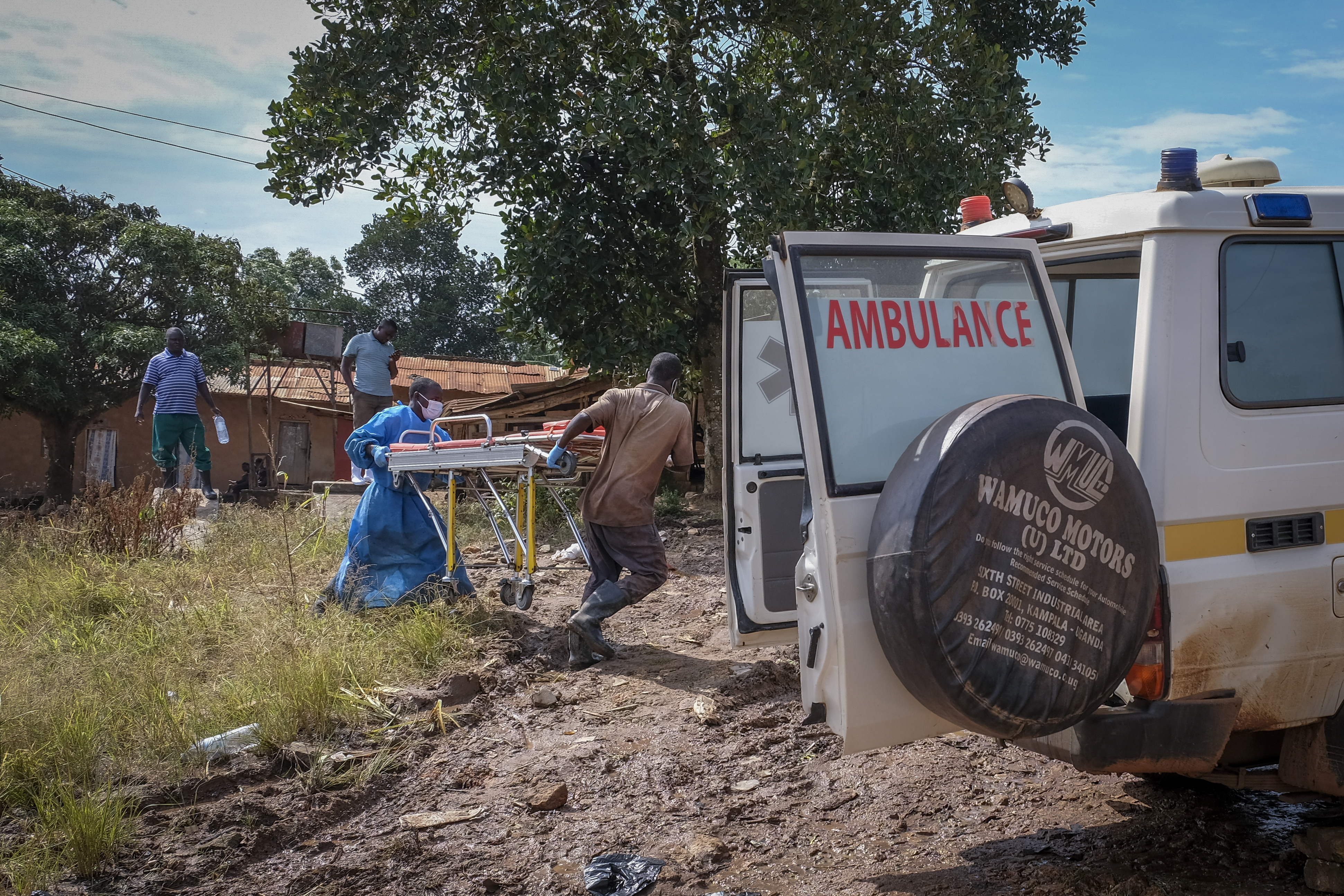 Men carry a stretcher used for suspected Ebola victims back to an ambulance after washing it, in the town of Kassanda in Uganda on November 1, 2022