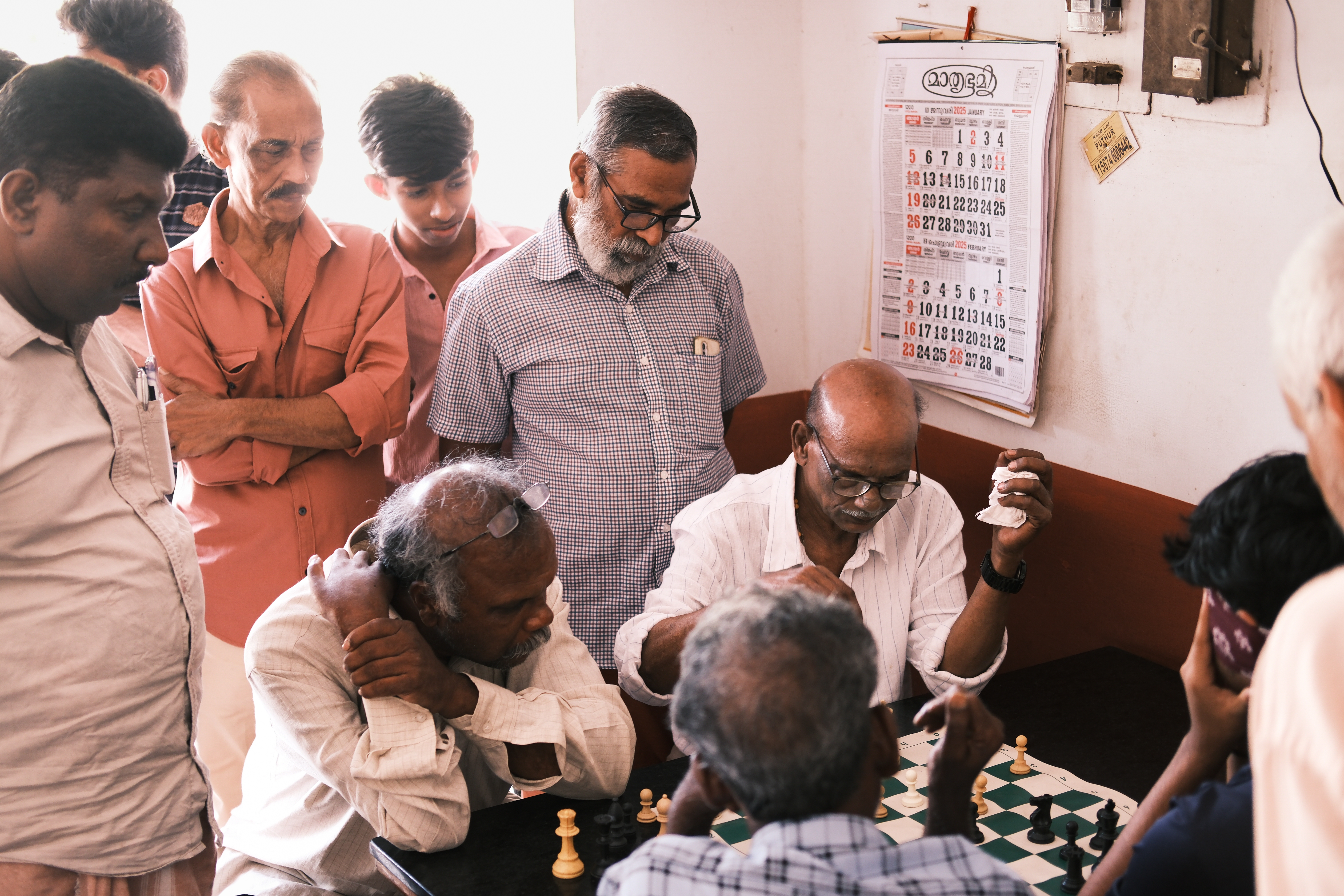 A crowd gathers around a chess game at a teashop in Marottichal, a sleepy village in India's Kerala state once known for alcoholism that's now fames for its chess [Mirja Vogel/Al Jazeera]