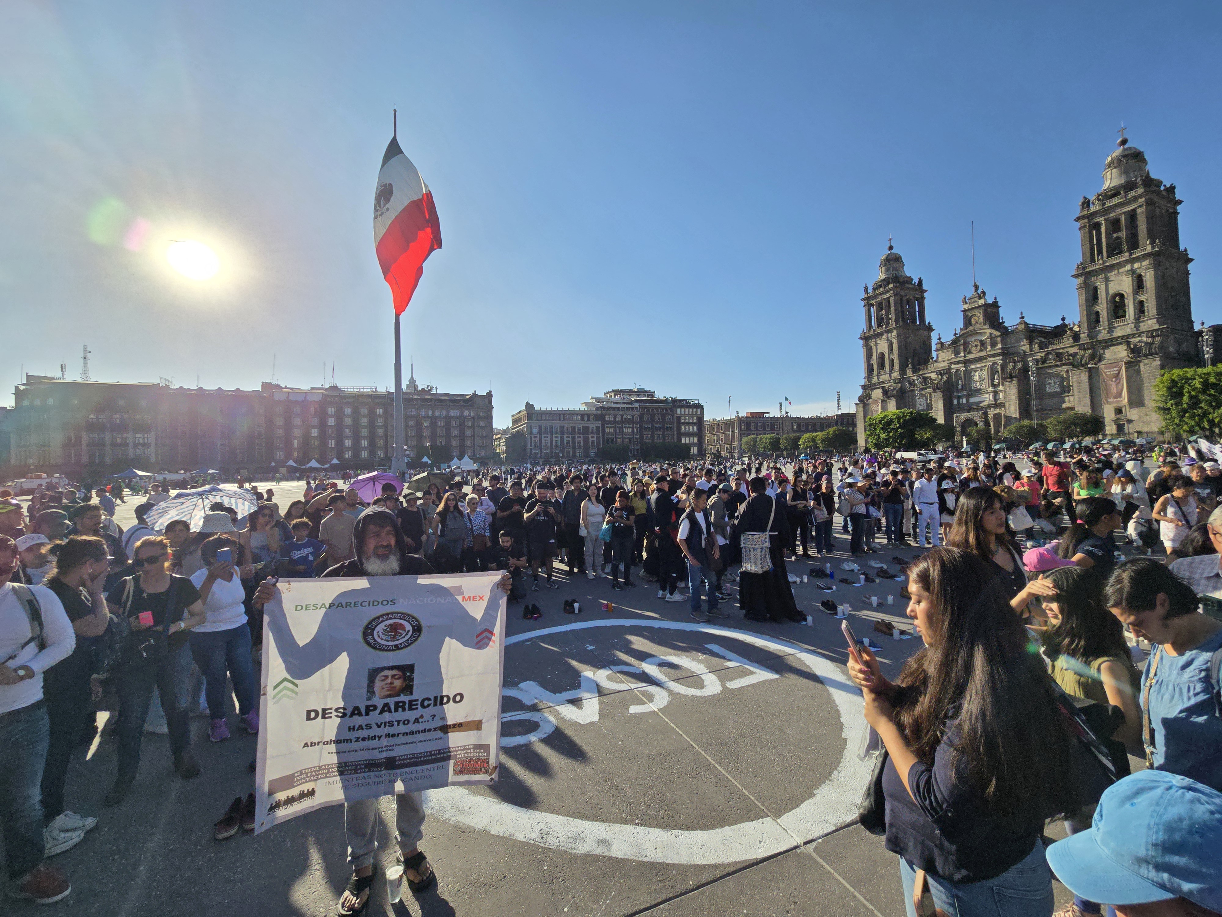 Gustavo Sánchez holds up a sign explaining his missing son's case at a protest in Mexico City's Zocalo plaza.
