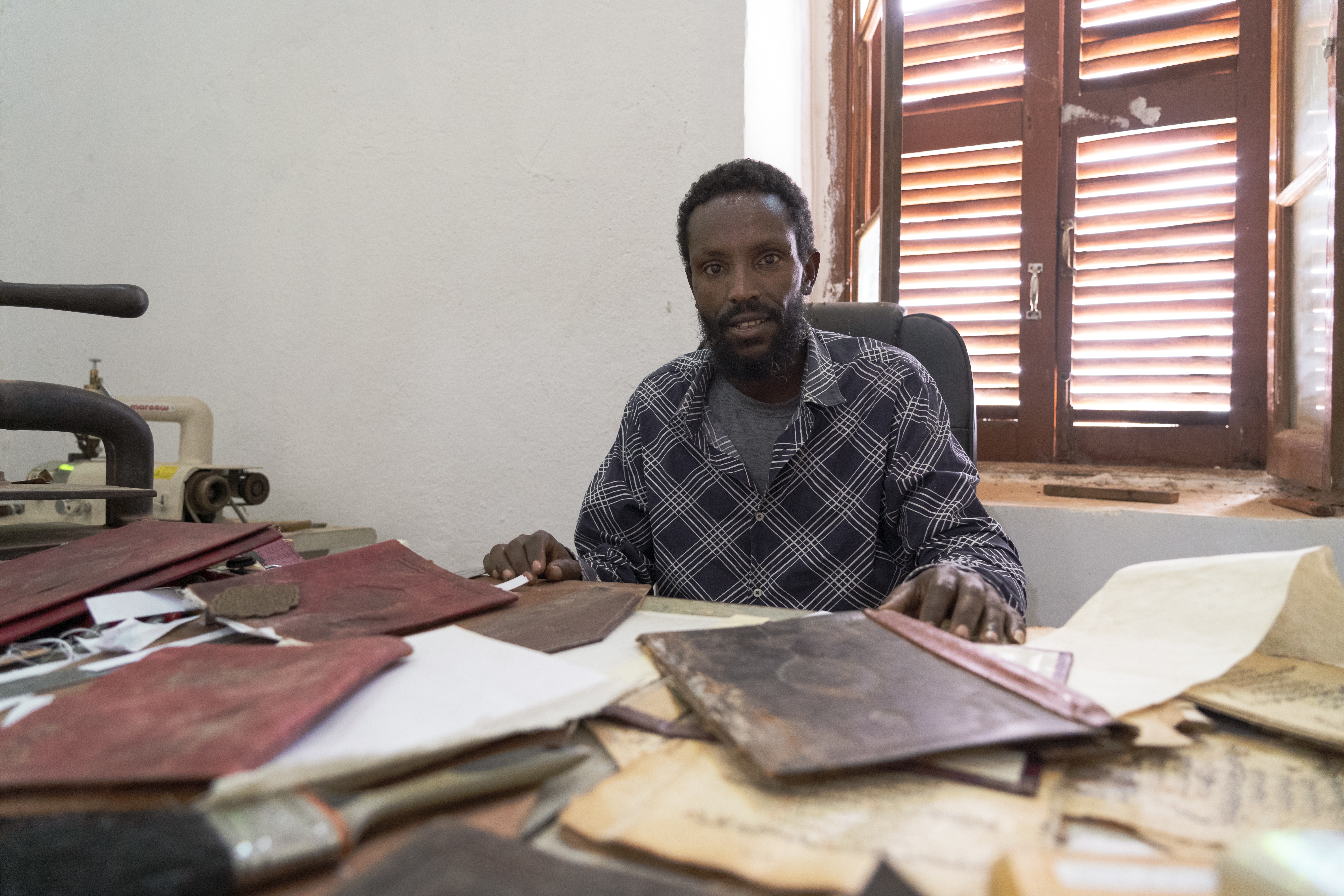 Bule sits at the museum workshop where he restores and binds manuscripts