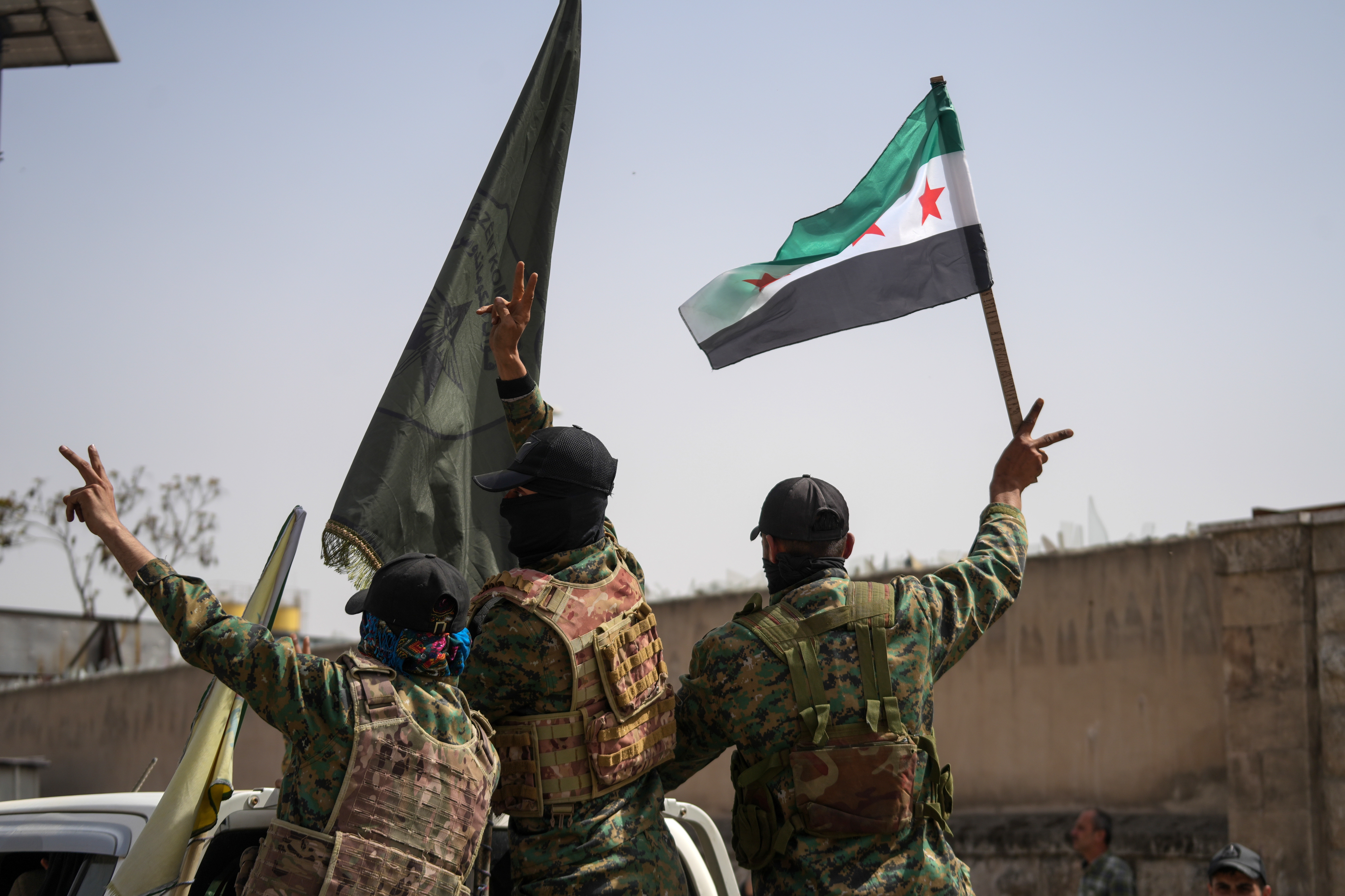 Members of the Syrian Democratic Forces (SDF) flash the victory sign while departing the city of Aleppo, Syria, on April 9, 2025.
