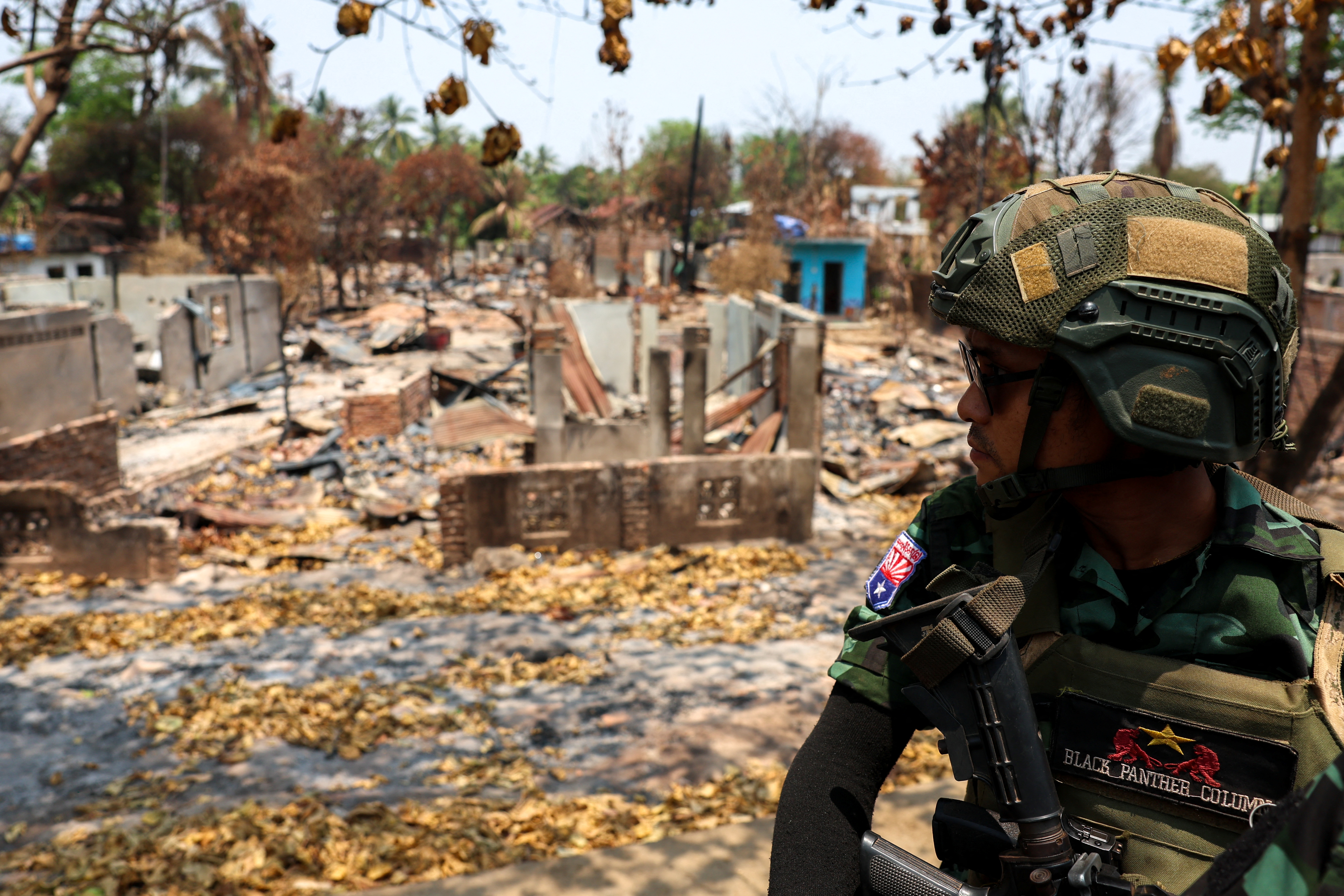A soldier from the Karen National Liberation Army (KNLA) patrols in a vehicle beside an area destroyed by an air strike in Myawaddy, a town under KNLA control, on April 15, 2024 [Athit Perawongmetha/Reuters]