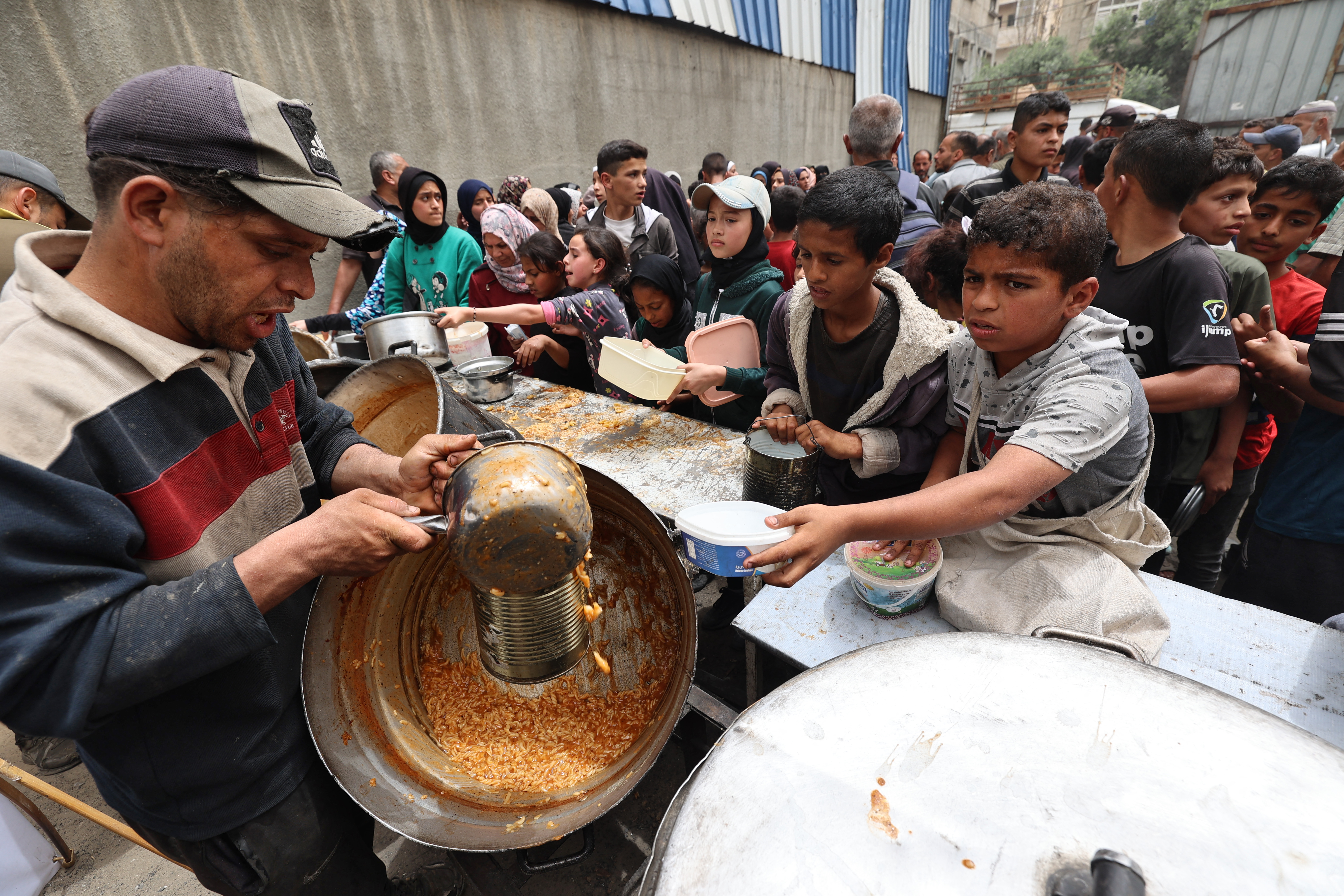 Palestinians gather to receive a hot meal at a food distribution centre in the Nuseirat refugee camp in the central Gaza Strip, on April 30, 2025.