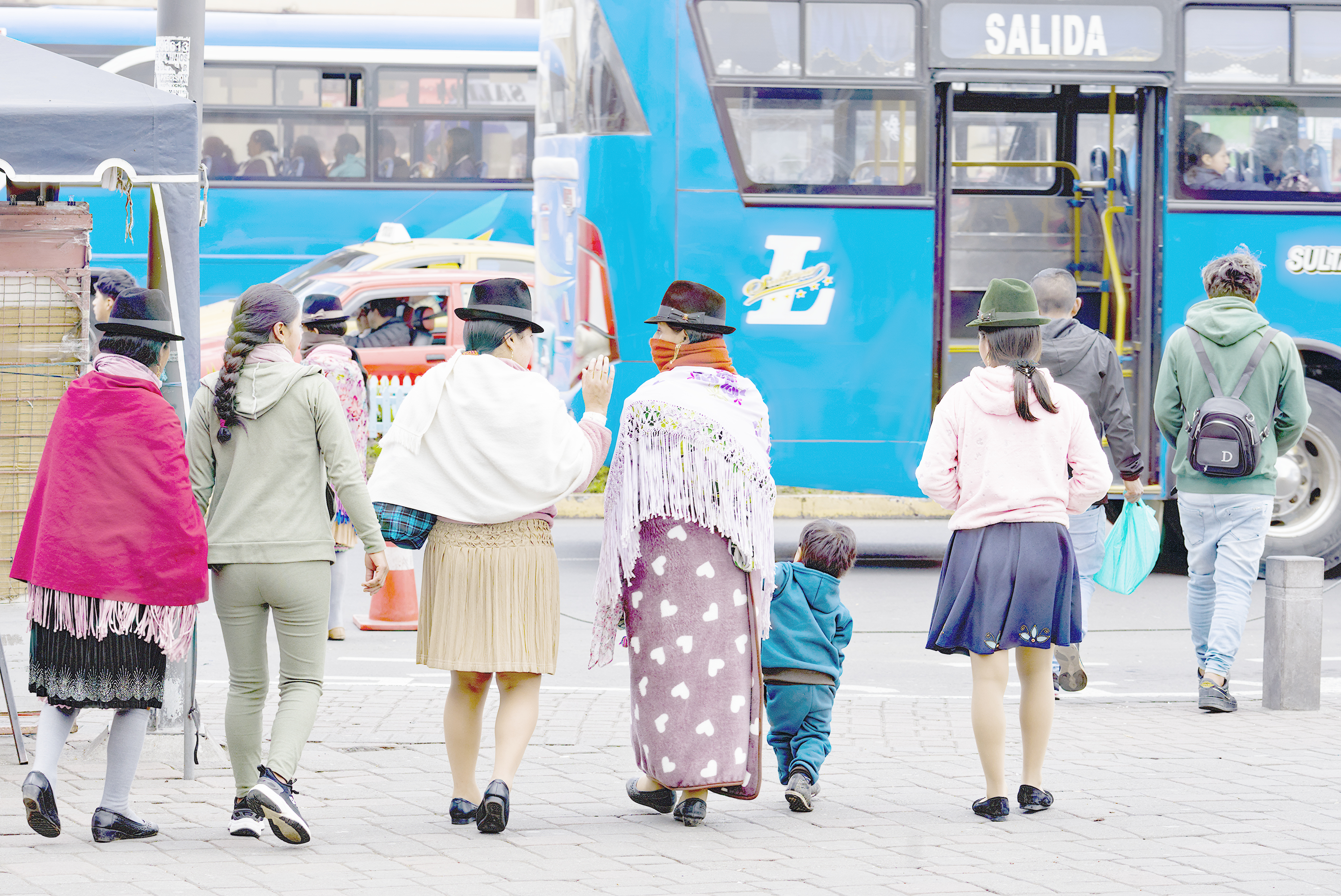 A line of Indigenous women walk down the street in Ecuador