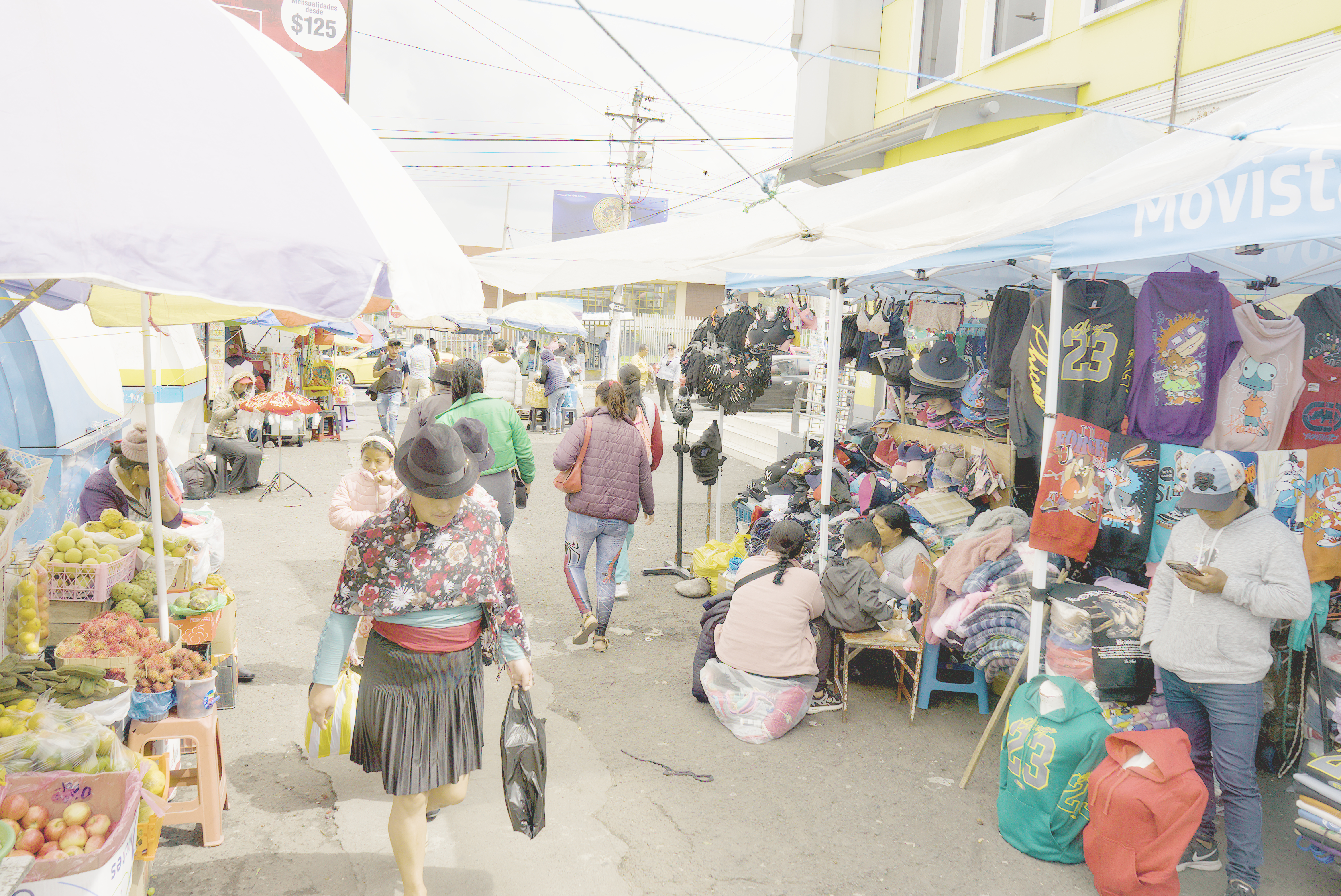 Shoppers walk through the stalls of an outdoor market in Latacunga, Ecuador