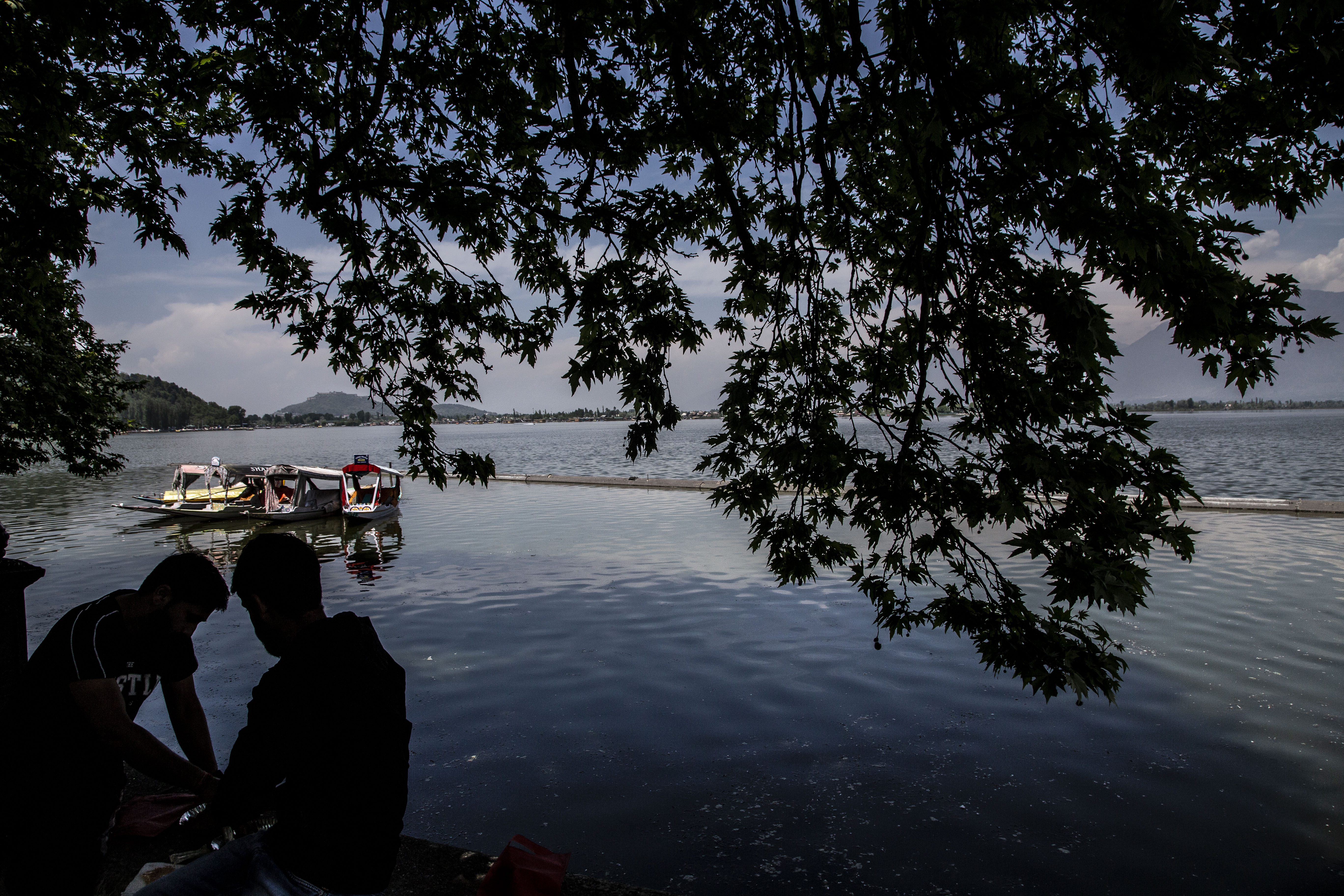 Tourists silhouetted sit on the bank of Dal lake on April 24, 2025, near Srinagar, Kashmir, India