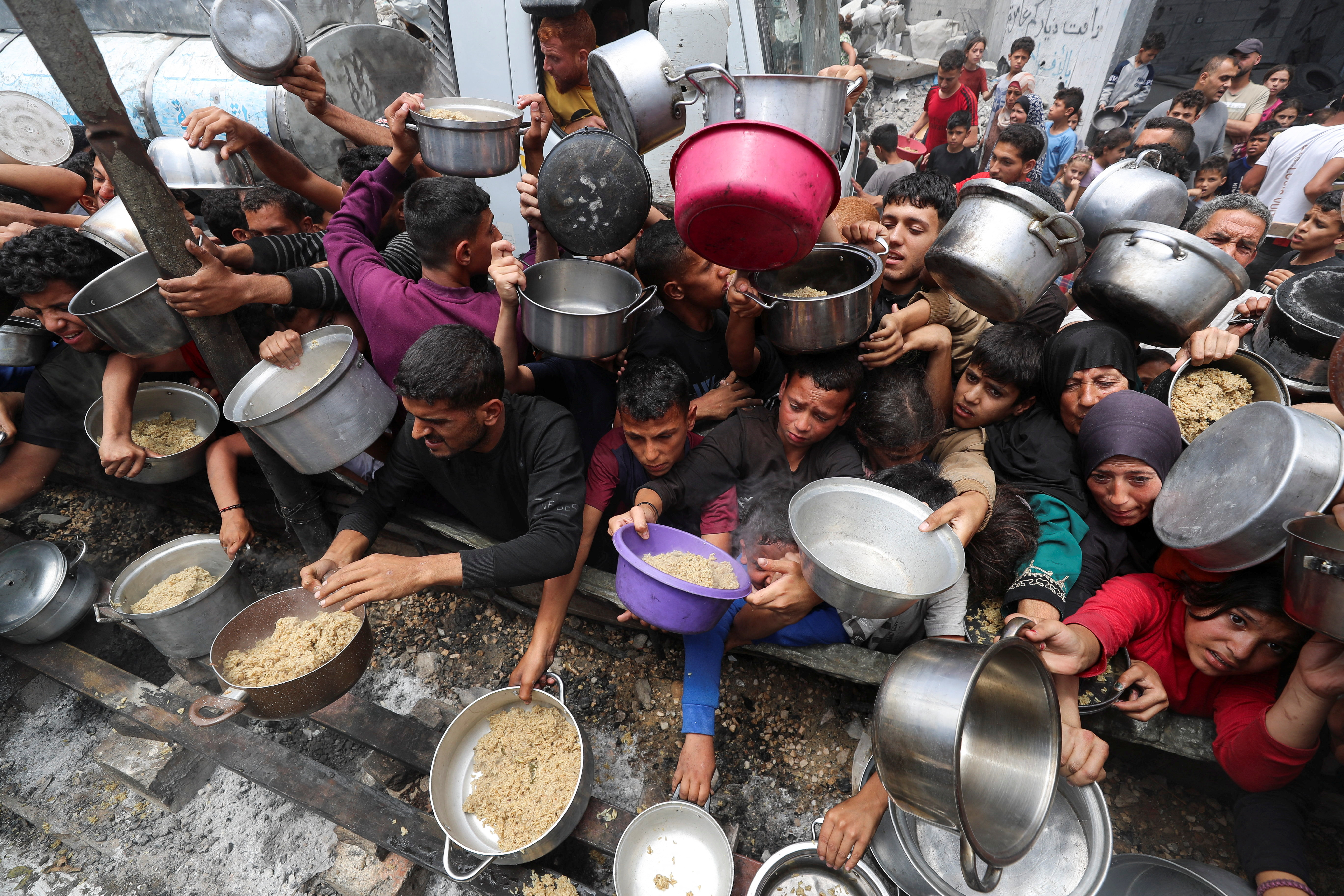 Palestinians wait to receive food cooked by a charity kitchen in Jabalia, in the northern Gaza Strip, on May 14, 2025