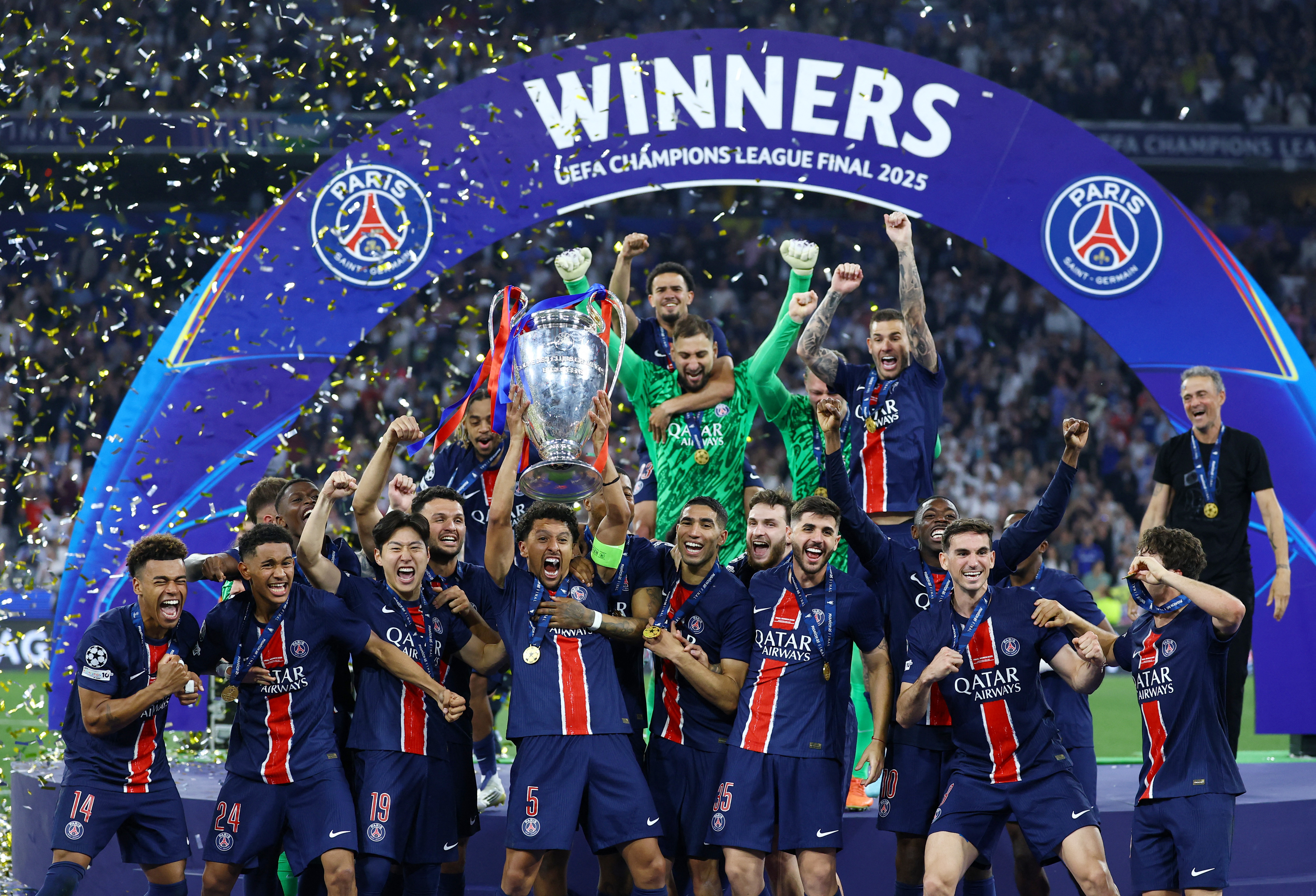 Paris St Germain's Marquinhos lifts the trophy as he celebrates with teammates after winning the Champions League