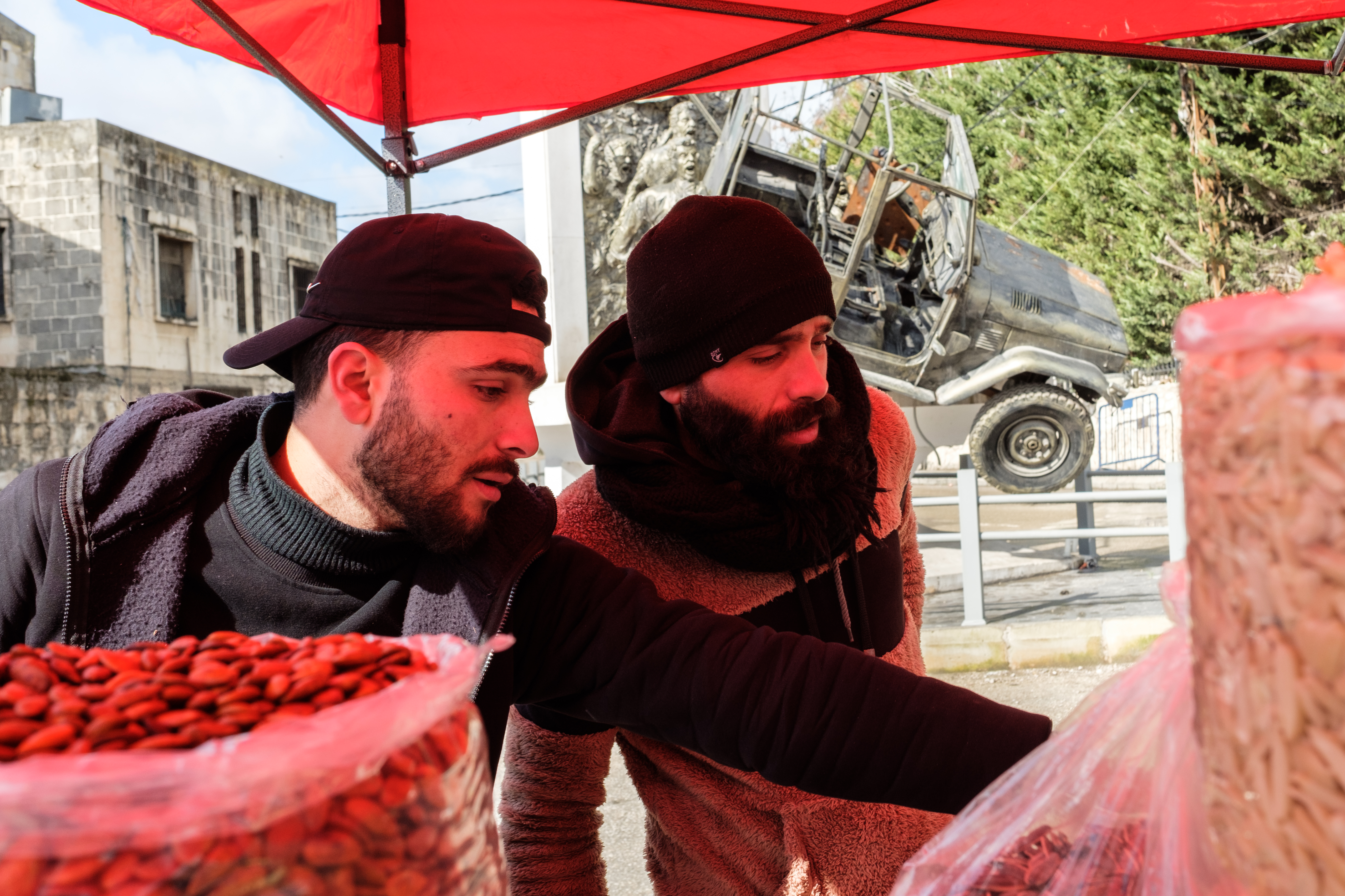 Rachid Dennawi and an employee help serve a customer at their candy and nuts stand at the Monday Souk in Nabatieh, Lebanon. February 24, 2025. [Rita Kabalan/Al Jazeera]