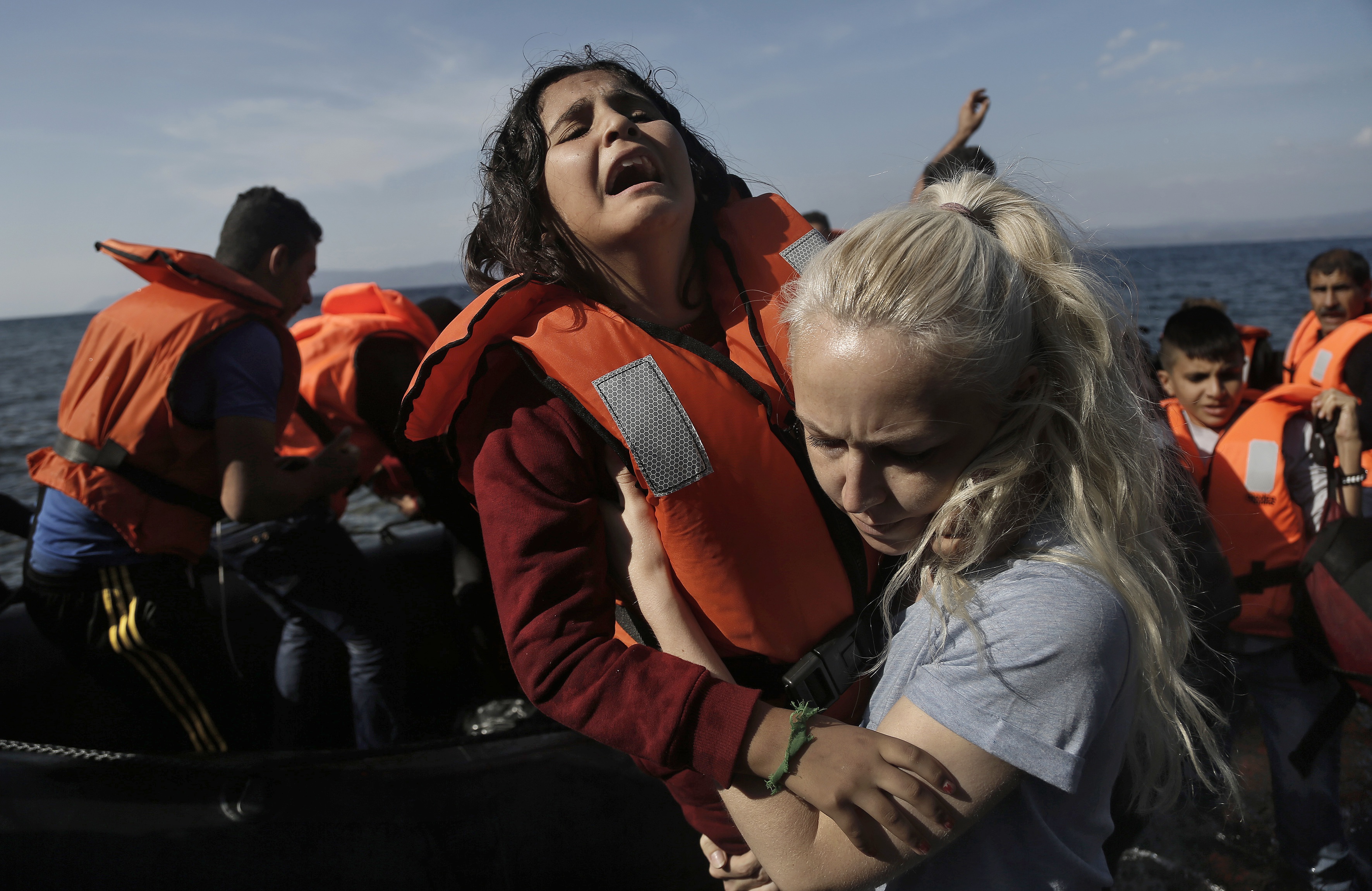A Syrian girl cries as she helped by a volunteer.