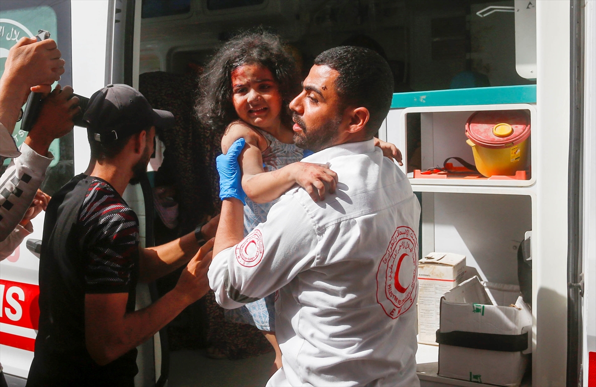a man carries a little girl with injuries out of an ambulance