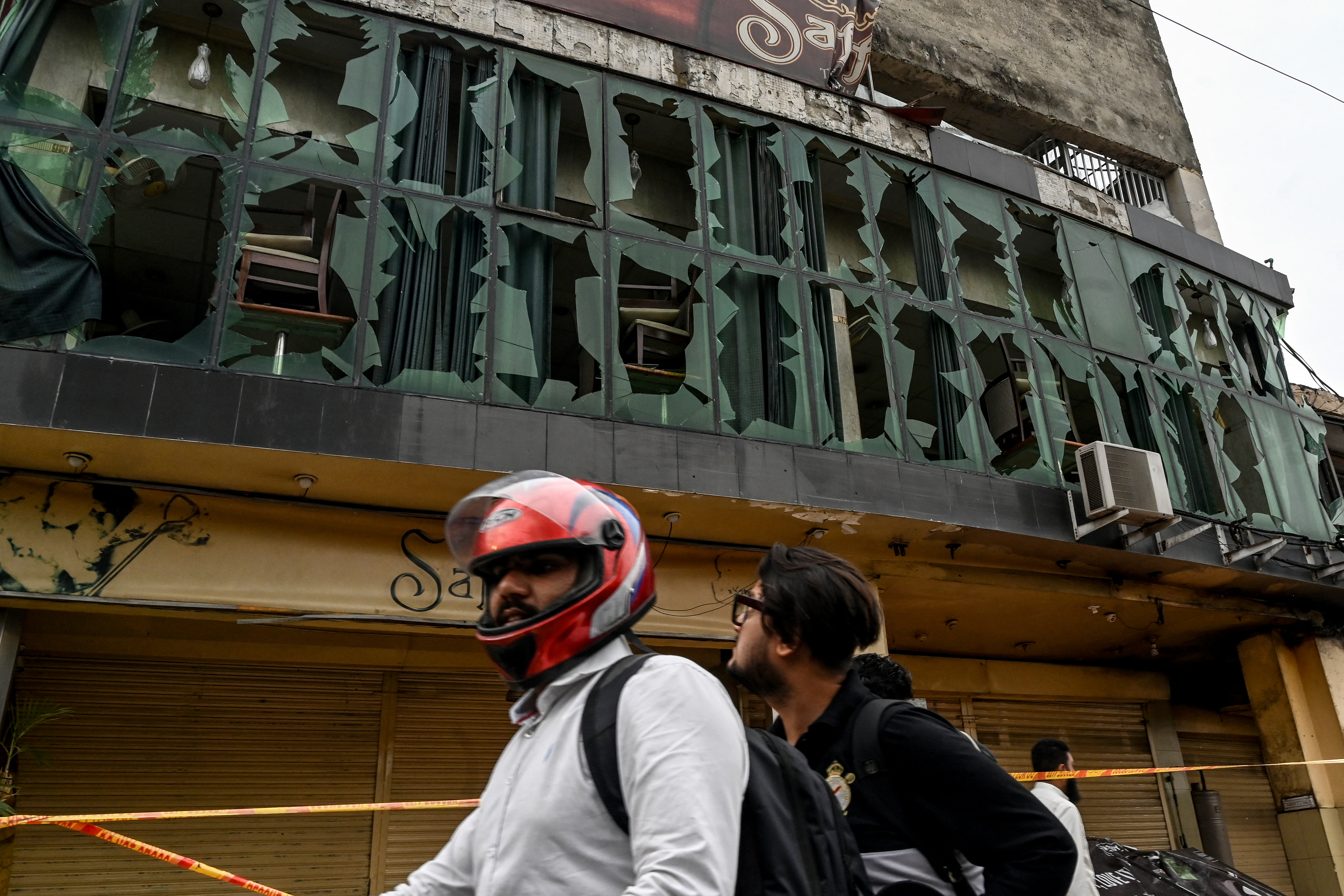 A motorcyclist rides past shattered glasses of a restaurant outside the Rawalpindi cricket stadium after an alleged drone was shot down in Rawalpindi on May 8, 2025. India and Pakistan accused each other on May 8 of carrying out waves of drone attacks, as deadly confrontations between the nuclear-armed foes drew global calls for calm. Pakistan's army said it shot down 25 Indian drones, while New Delhi accused Islamabad of launching overnight raids with "drones and missiles", and claimed it destroyed an air defence system in Lahore. (Photo by Aamir QURESHI / AFP)