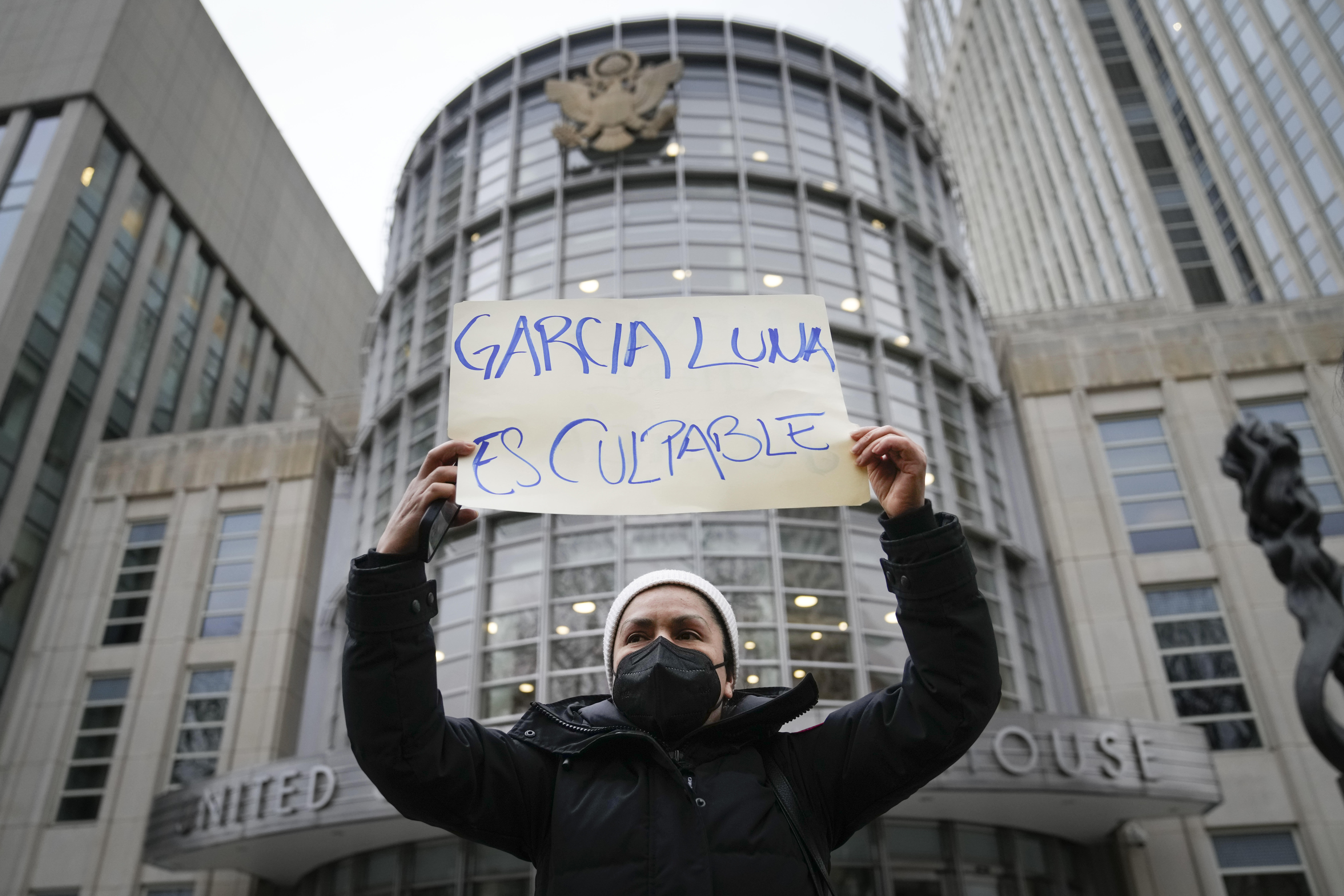 A protester holds a sign that reads, "GARCIA LUNA ES CULPABLE"